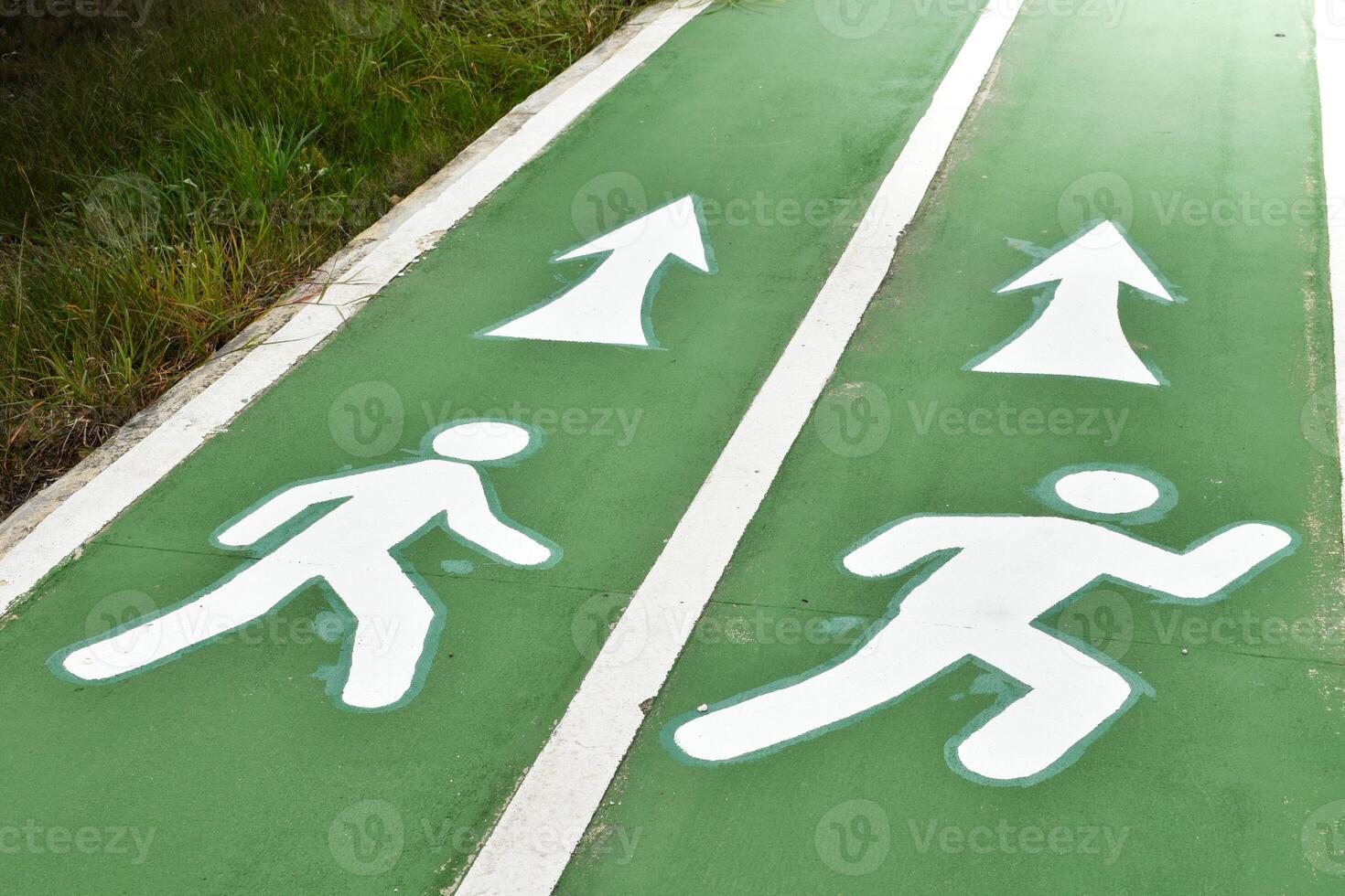 White lane lines divide walking or running lanes on green road surfaces exercise for towards the light at outdoor park in grass and sunlight background concept of exercise options. photo