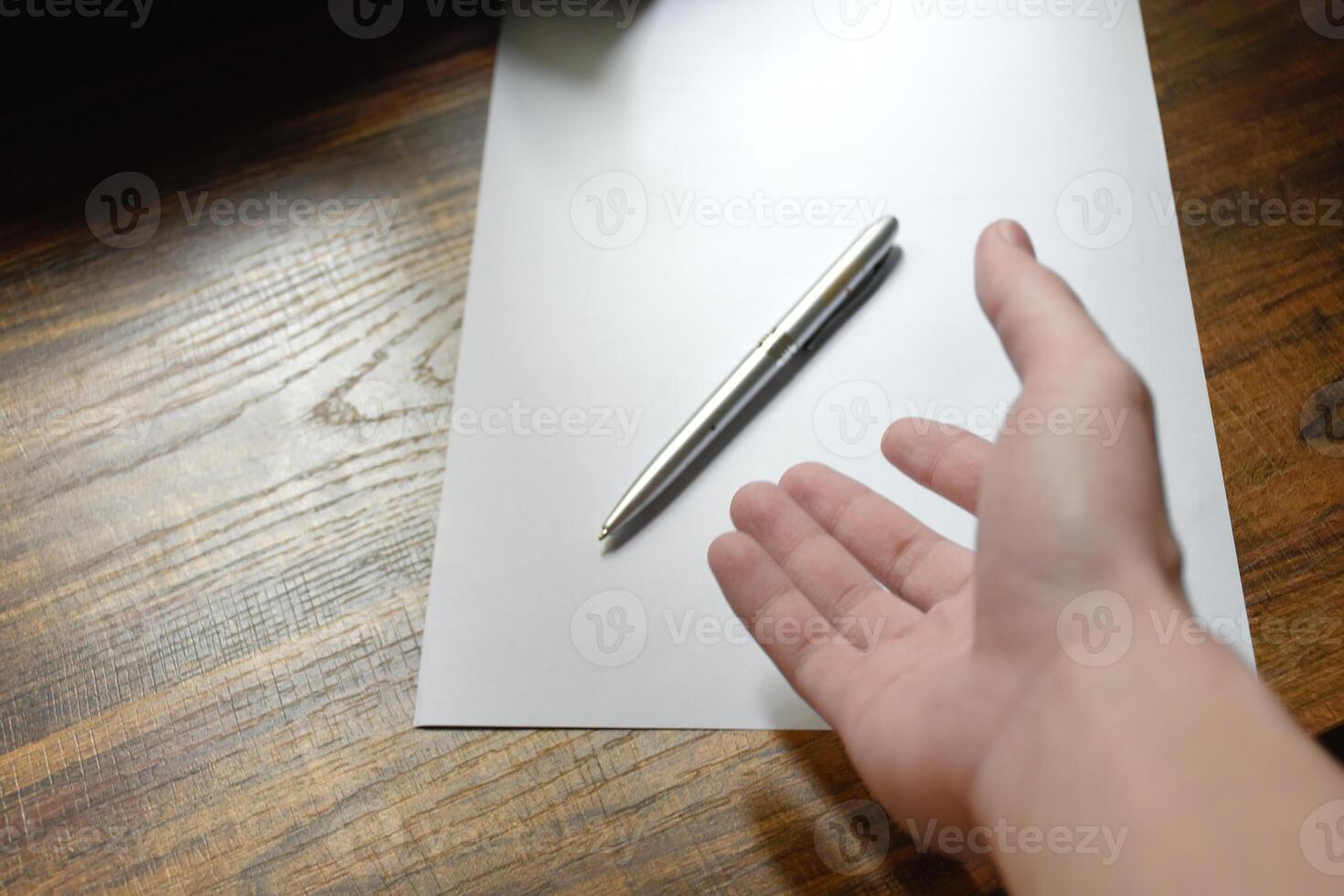 Hand with pen over blank paper on wooden work desk beautiful pattern,Hand reaching for pen,concept of idea and actions, Work equipment in workplace,Hand close-up with pen and paper,note idea for work. photo