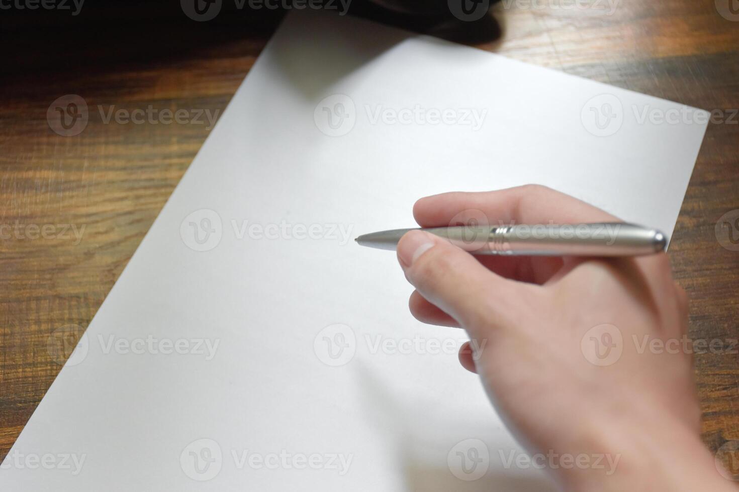 Hand writing with pen over blank paper on wooden work desk beautiful pattern,concept of idea and actions,Hand holding for pen,Work equipment in workplace,Hand close-up with pen and paper. photo