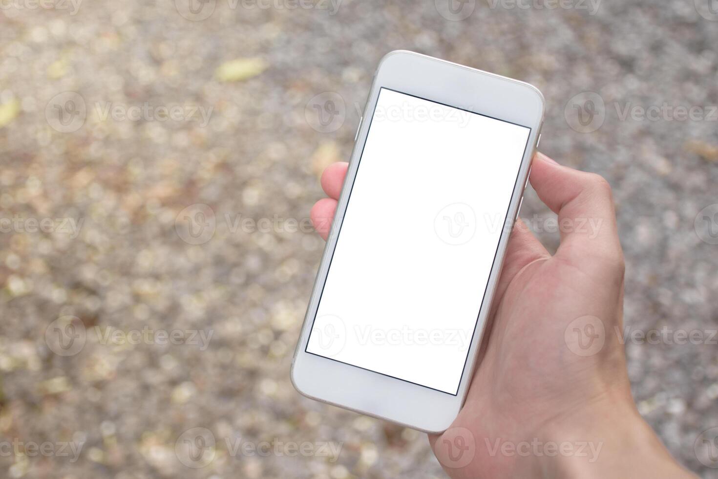 Close up of man hand holding modern smartphone mockup with blank white screen. Hand showing white screen of smartphone in ground blurred background. photo
