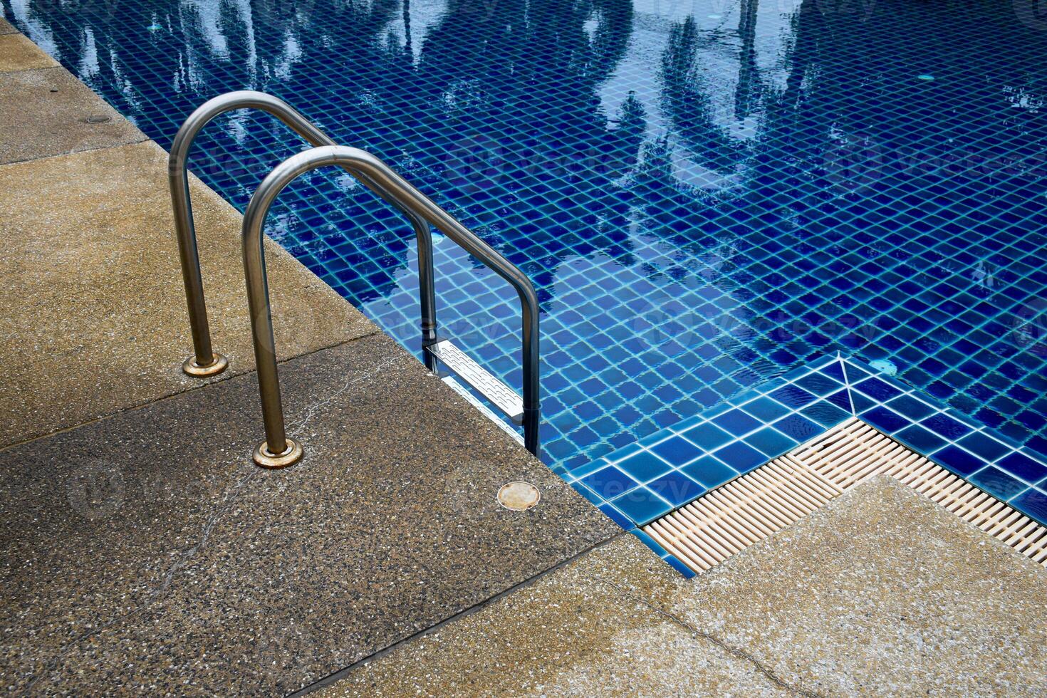 View of the swimming pool and swimming pool ladder decorated with gravel walkways in vintage tones. photo
