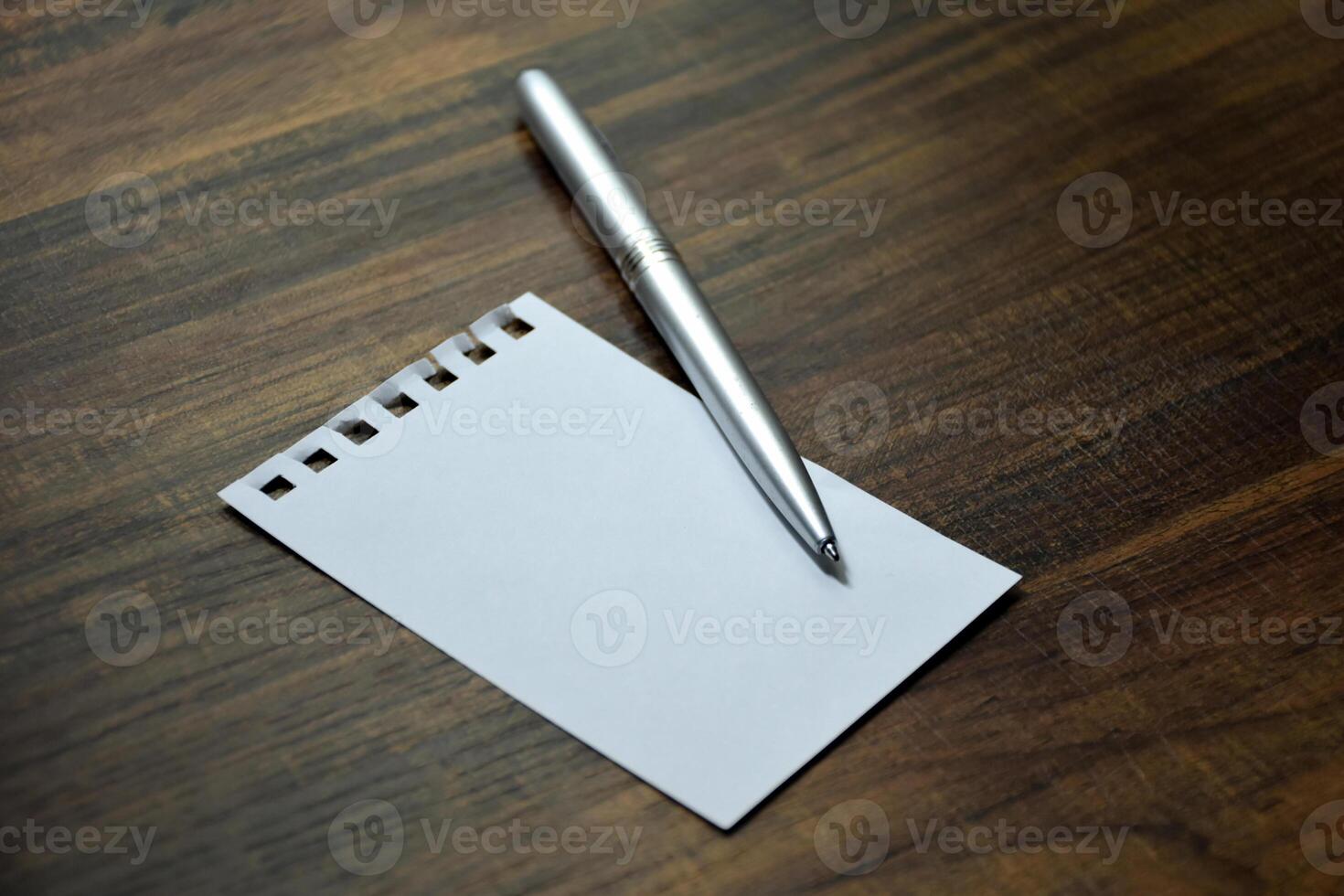 Blank white paper and silver metal pen on the work desk beautiful wooden pattern. photo