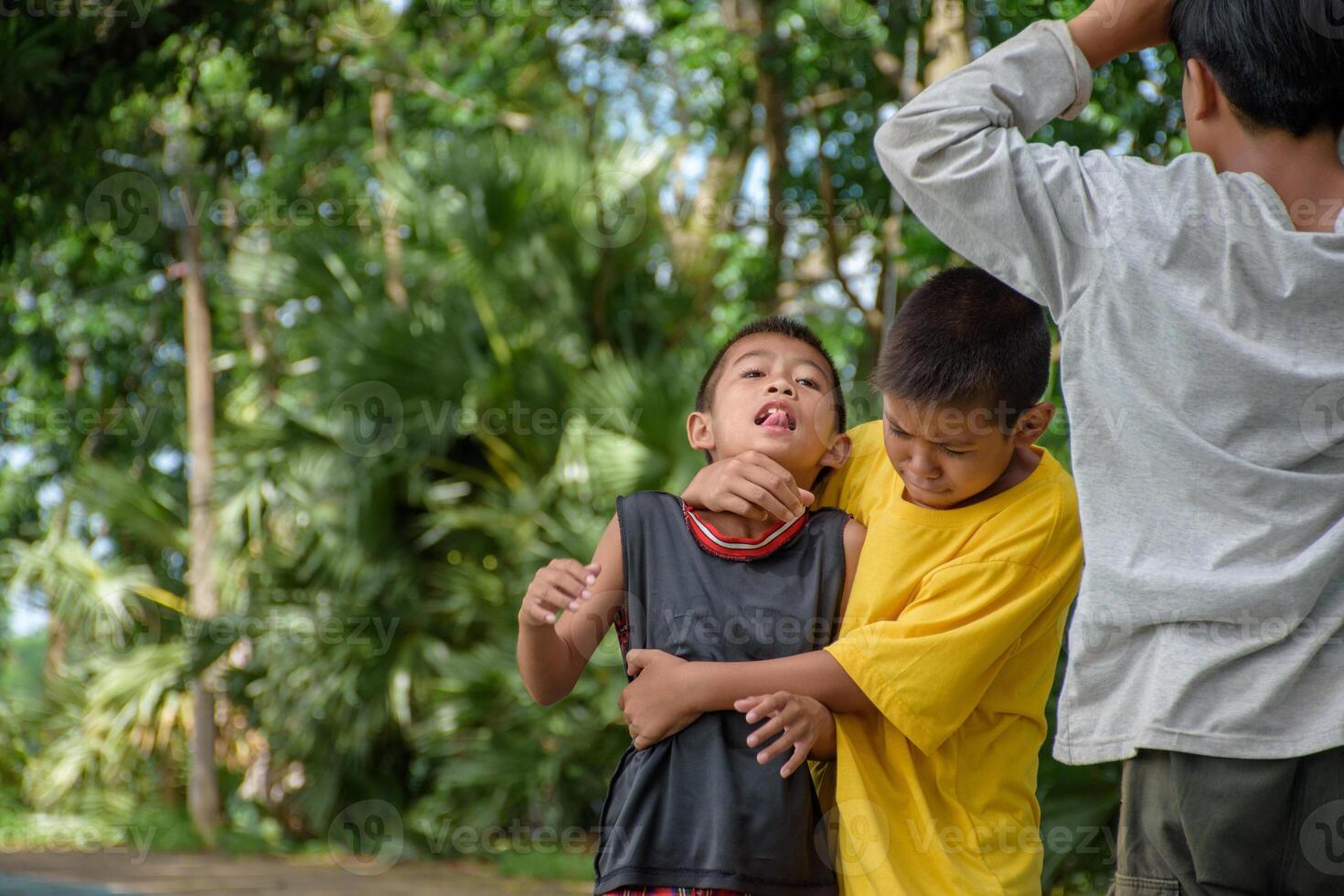 Group of children were fighting and physically attacking each other due to childhood bullying and school violence at outdoor park in forest blurred background. photo