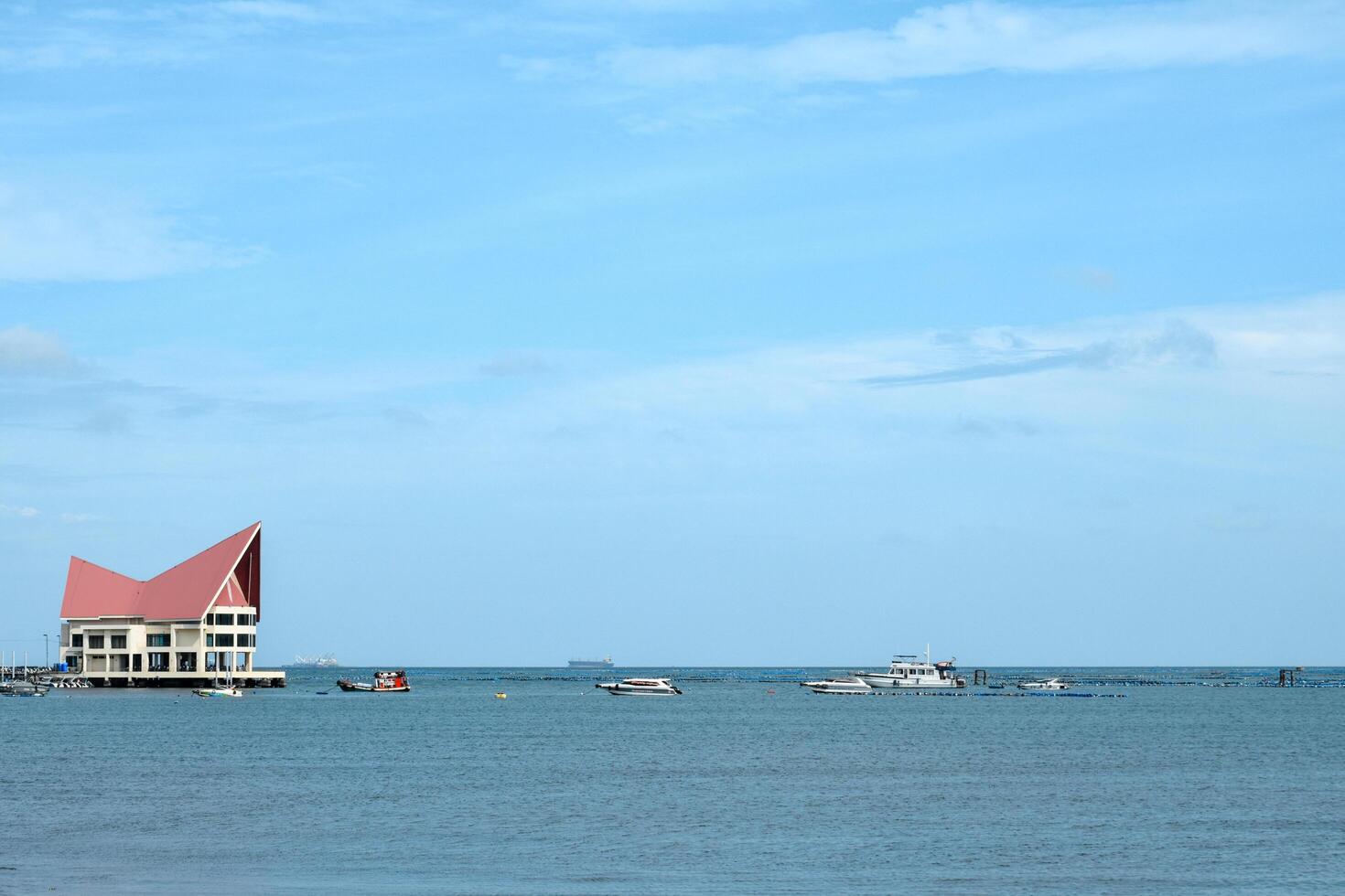 Chonburi, Thailand , August 5, 2023, Modern building on the floating island in middle of the sea called the Koh Loy at Sriracha is a public space and fishing boats and passenger ships at sea. photo