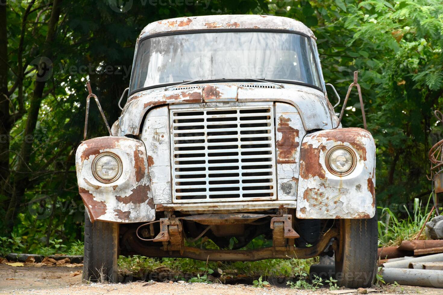 Abandoned classic truck and has rust font-view at old storage place in natural forest and scrap metal background for concept of cars and transportation. photo