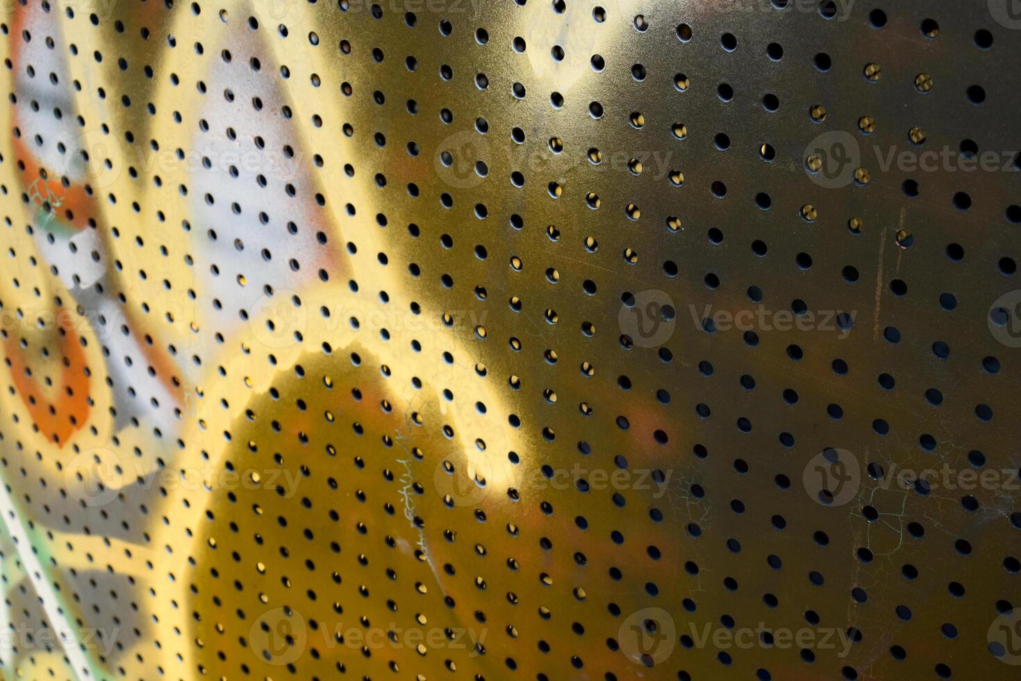 Close-up a metal surface with many holes between it and different colors smeared on the surface creates a beautiful pattern in a vintage tone background. photo