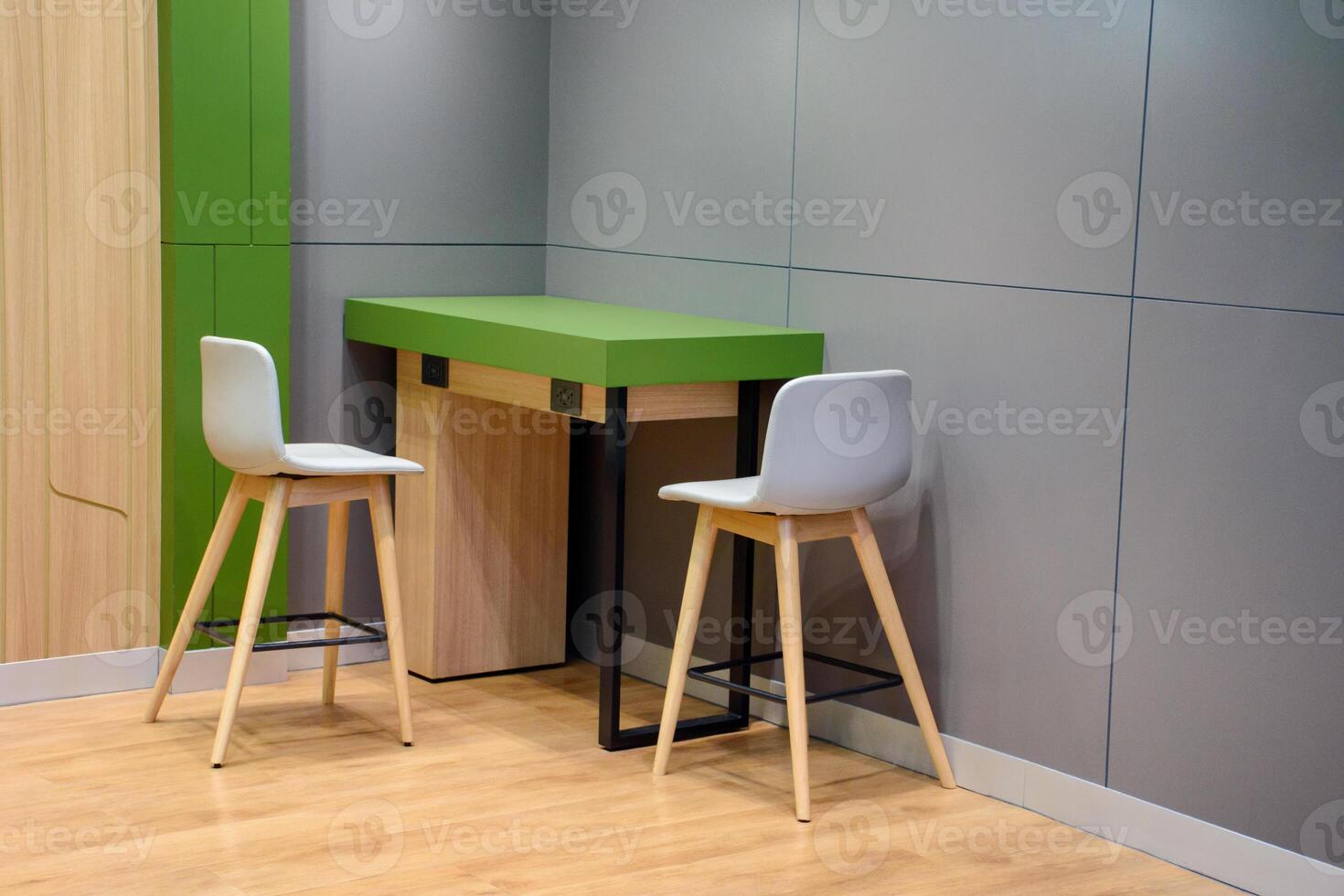Modern style interior design with gray and green wall with two office chairs and wooden table on wood pattern floor with soft light for concept of work desk and relaxing room. photo