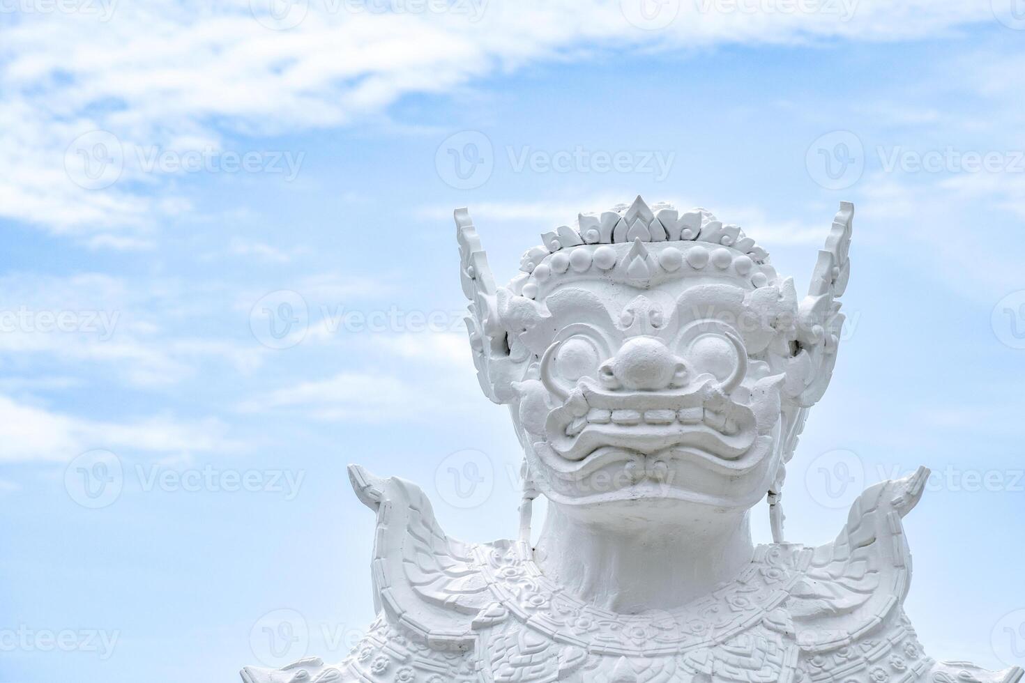 Statue of a white giant with Thai cultural patterns in Thai temples and important places against a blue sky background. White sculpture of a giant with a terrifying face. photo