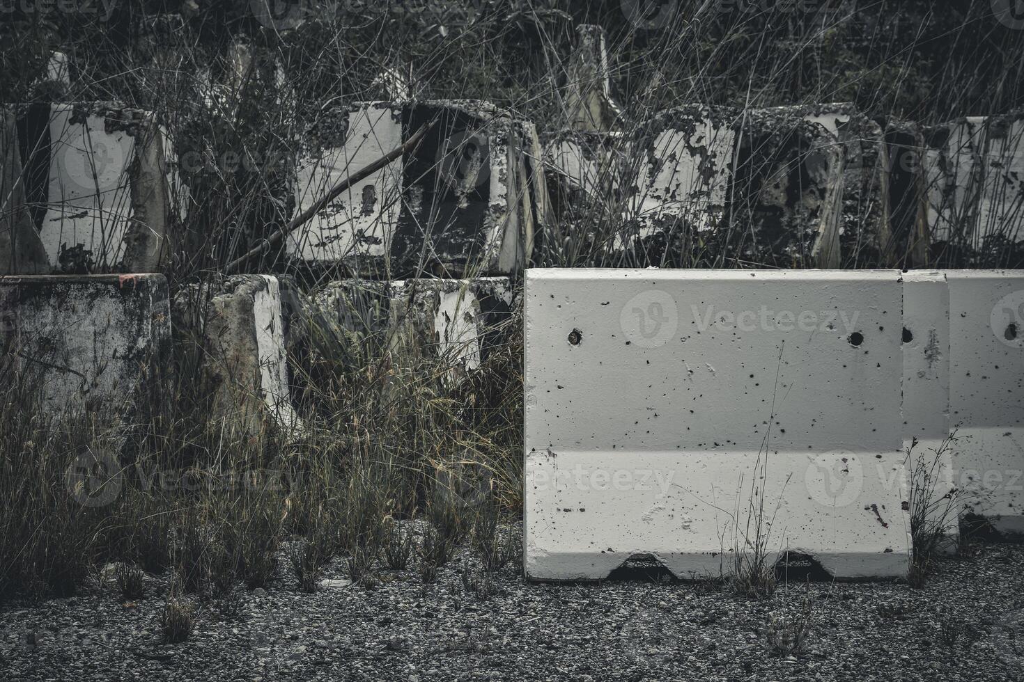 Broken concrete barrier blockroad and ruins are piled high at a derelict junkyard against a dark tone cinematic background. photo