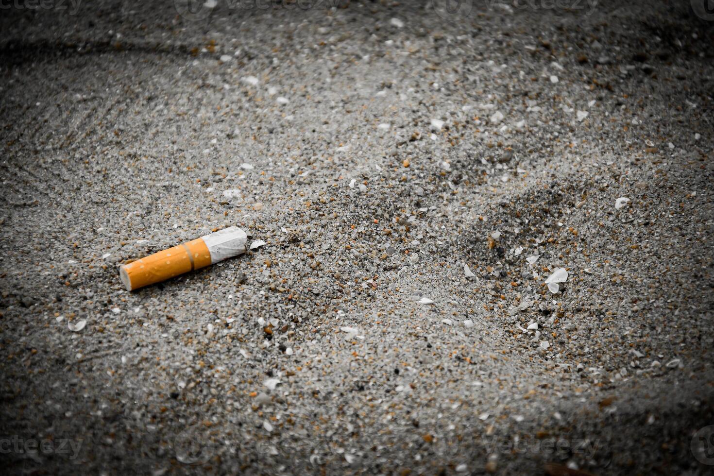 Fag-End or Cigarette butts on the sand at the beach side have a negative effect on the marine environment for no smoking concept on a dark vintage tone background. photo