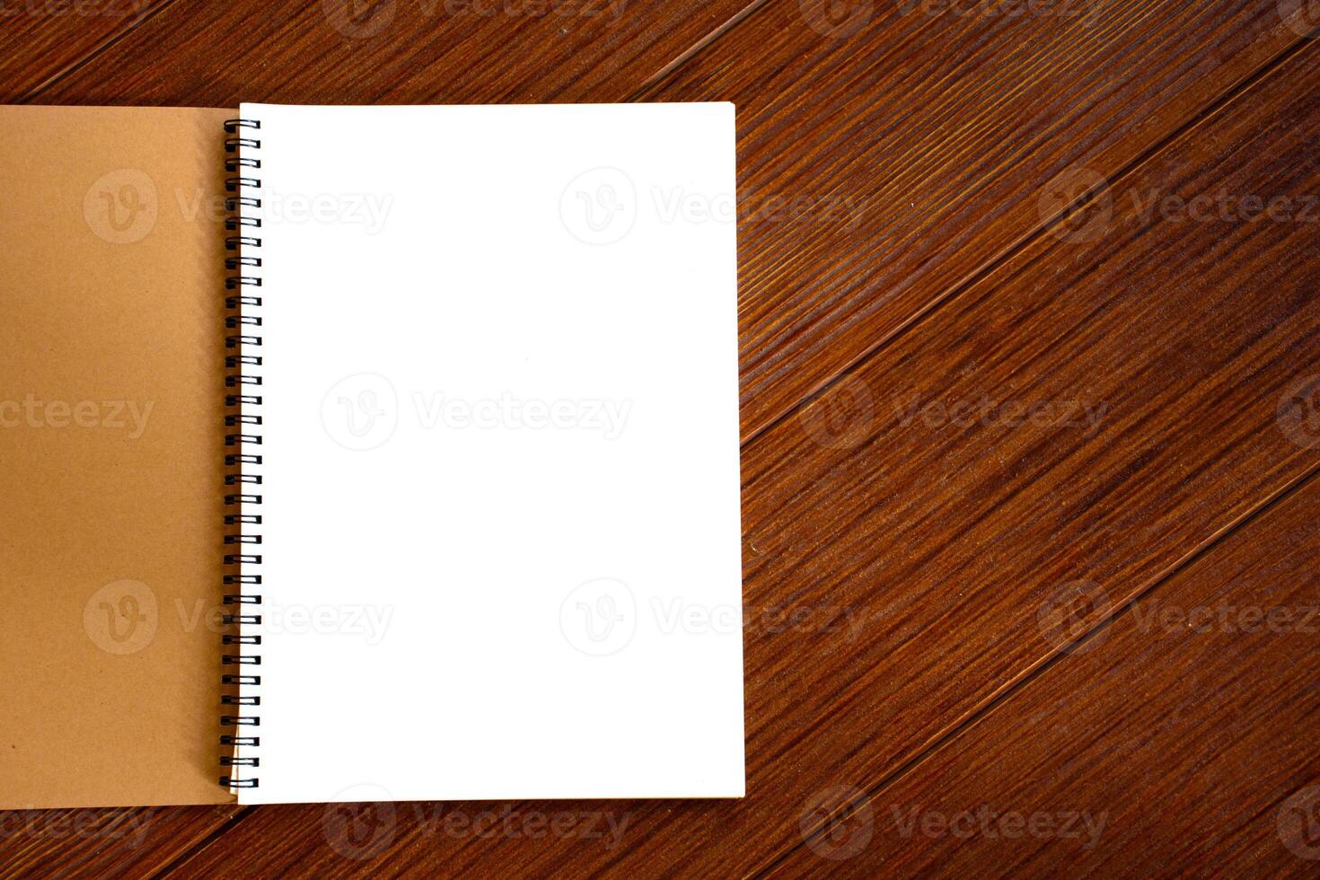 White blank page of notebook on brown wooden beautiful pattern background is a copyspec for the idea concept. Empty white blank notebook and paper texture background. photo