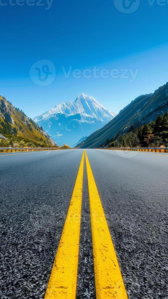 Empty Road Leading to Snowy Mountain Peak in Valley Landscape. photo