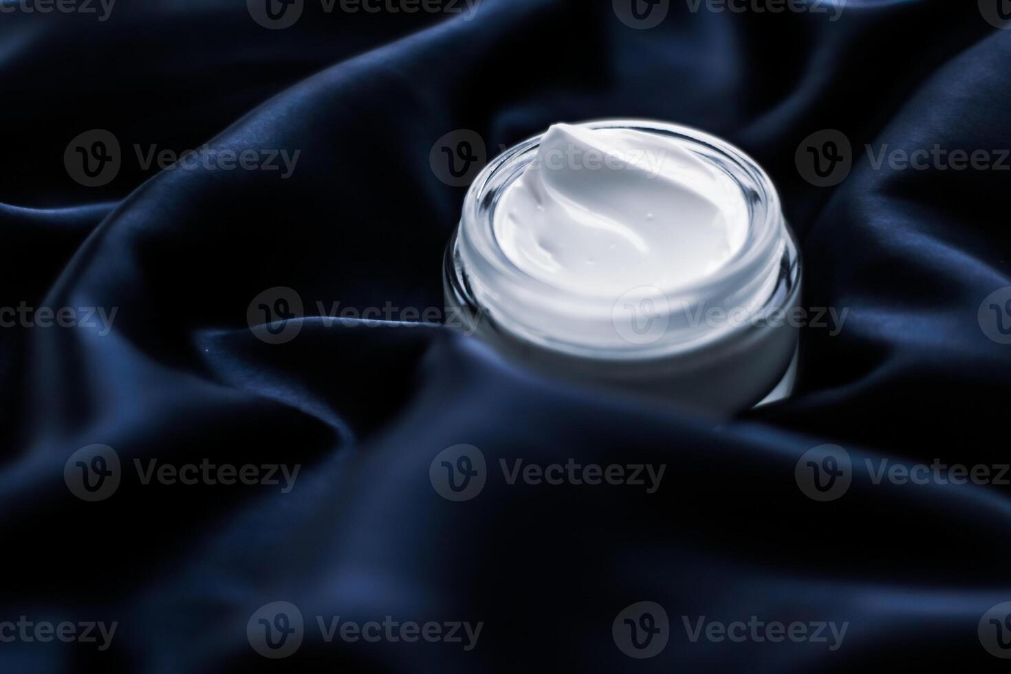 Luxury face cream jar on a dark blue silk photo