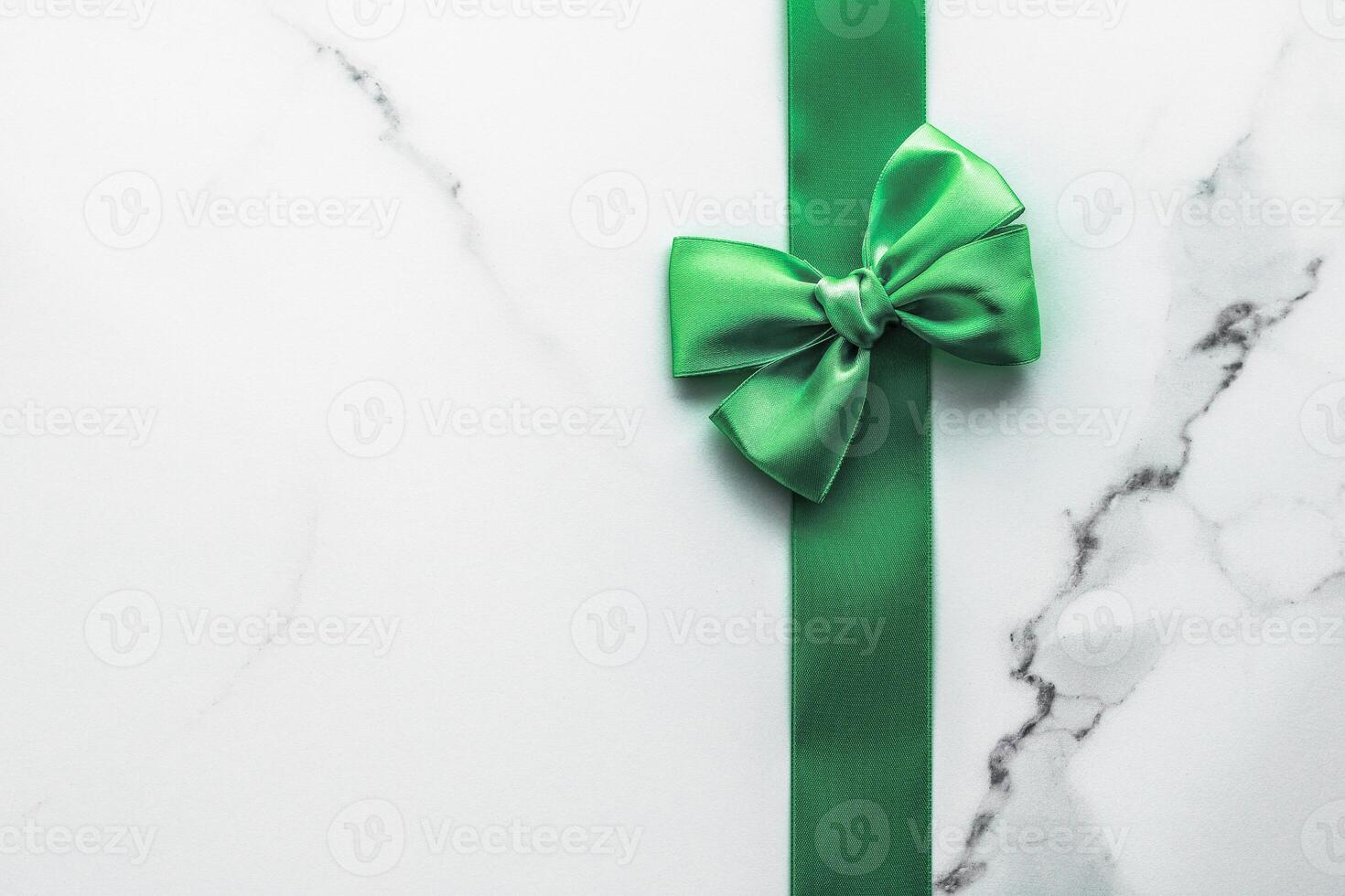 Green silk ribbon and bow on marble background, St Patricks day present or Christmas glamour gift decor for luxury digital brand, holiday flatlay design photo