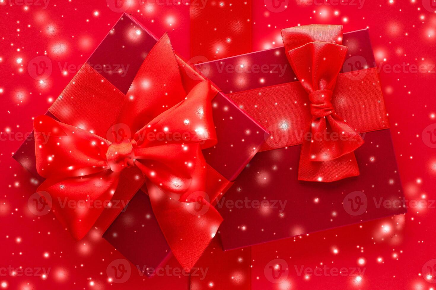 Winter holiday gifts and glowing snow on red background, Christmas presents surprise photo