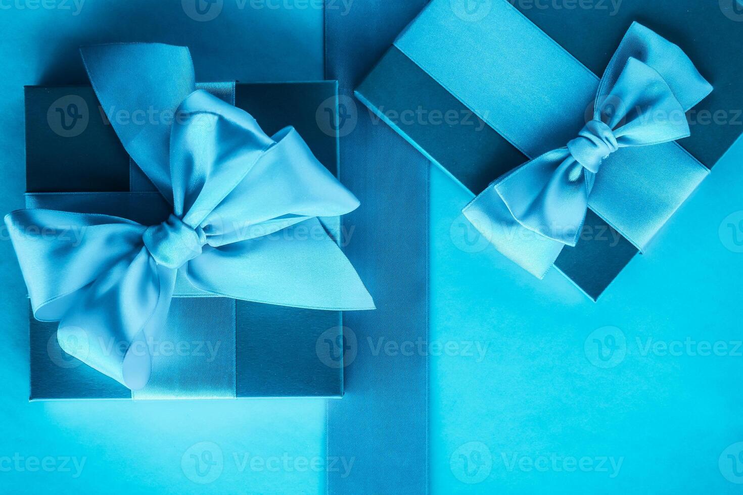 Luxury holiday gifts with silk ribbon and bow on blue background photo