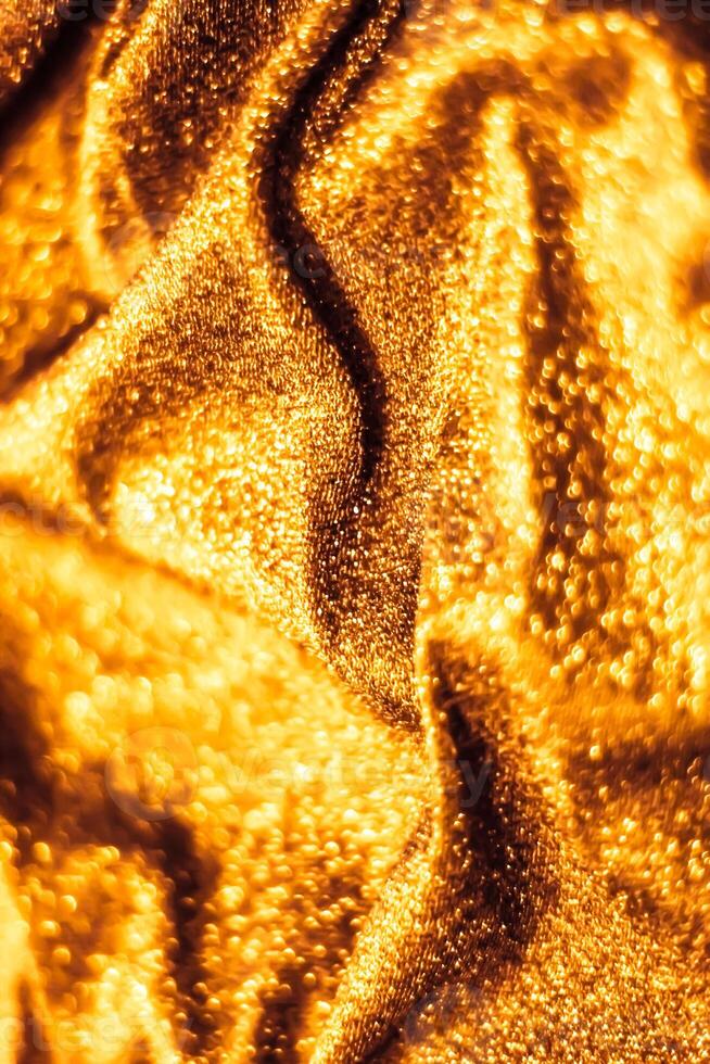 Golden holiday sparkling glitter abstract background, luxury shiny fabric material for glamour design and festive invitation photo