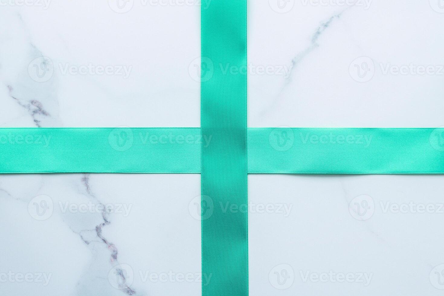 Green silk ribbon on marble background, top view photo