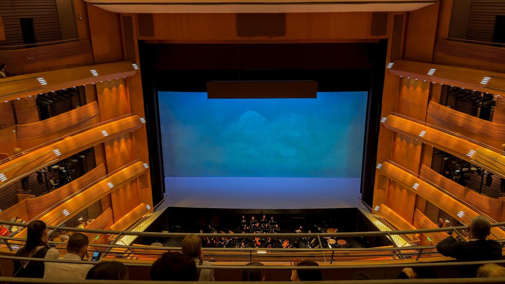 Audience awaiting performance in modern theater with orchestra pit, wooden interiors, and blue lit stageideal for cultural events and performing arts concepts10 dec 2023, Saint Petersburg Russia photo