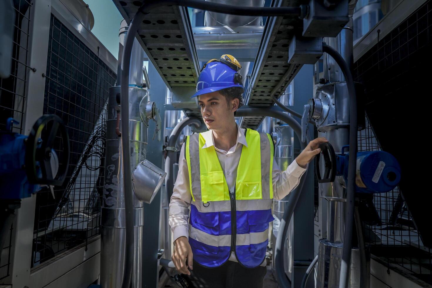 An industrial worker in high-visibility gear and a blue helmet meticulously examines the intricate network of machinery. The engineer is dedicated to maintaining operational efficiency and safety. photo
