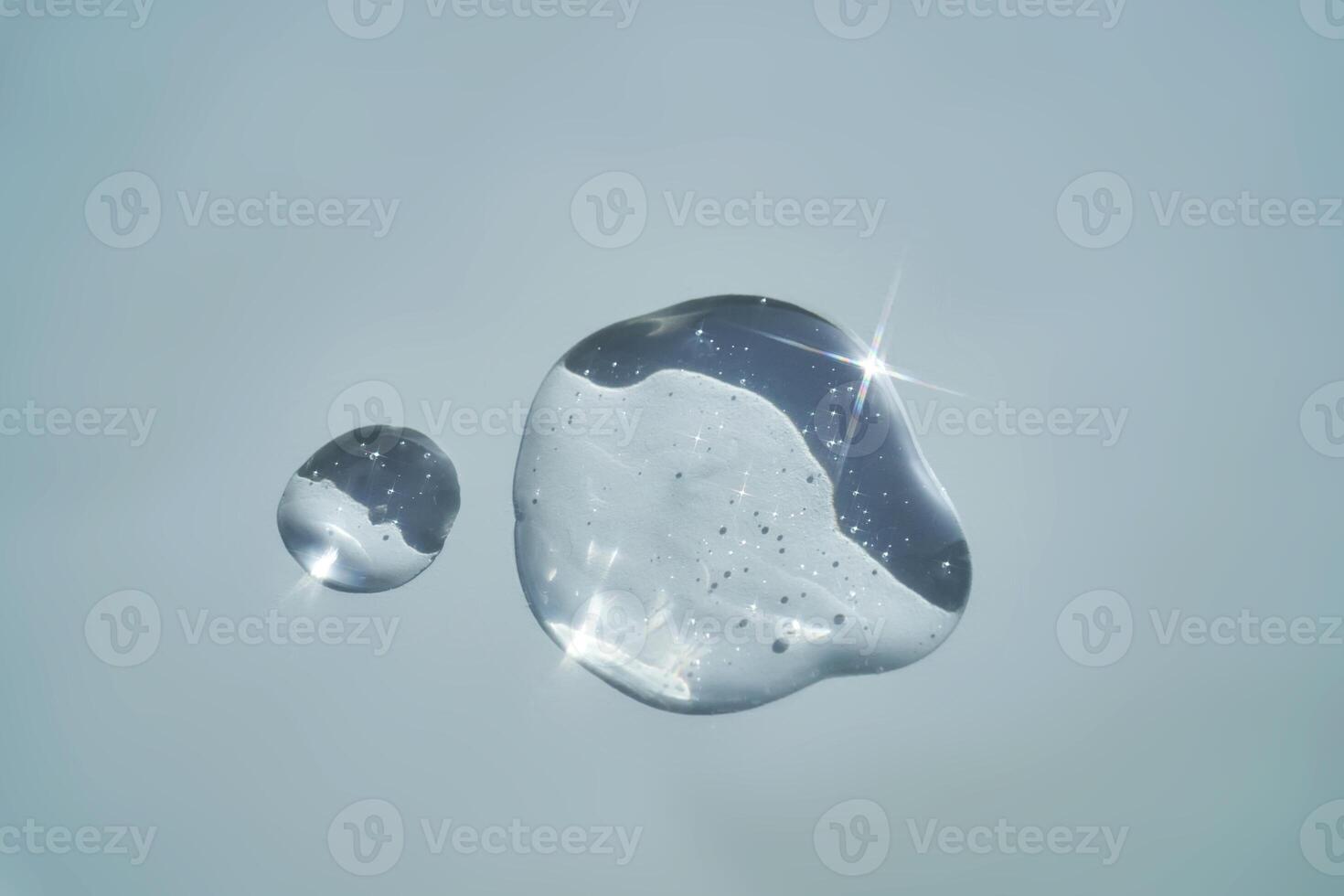 Drop of serum shimmering in the sun on a blue background. photo