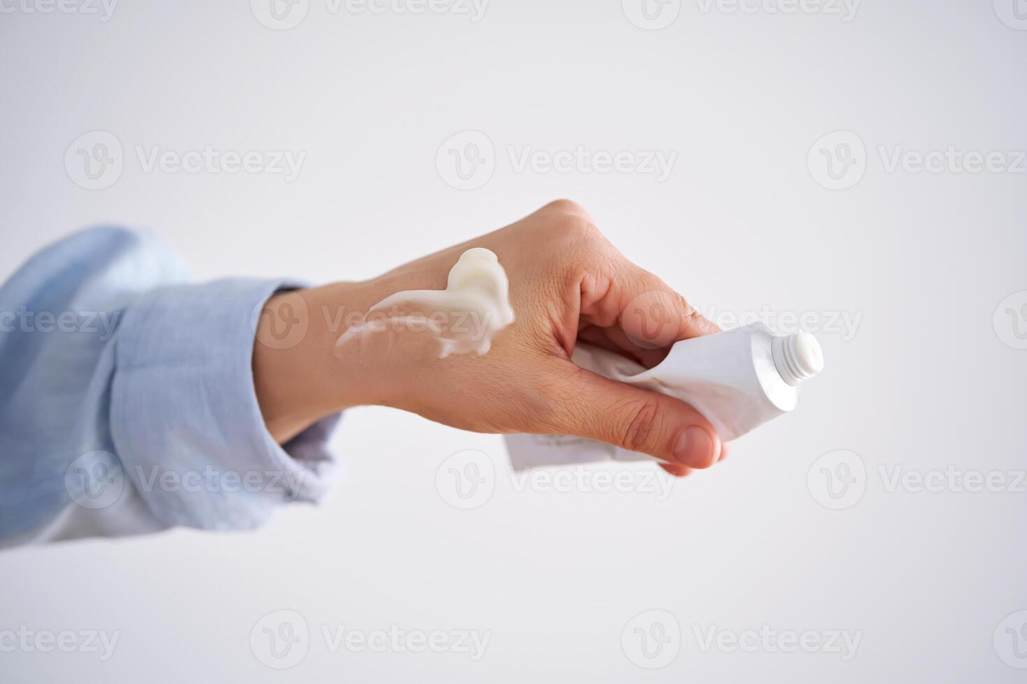 Hands in a blue shirt hold a tube of cream. photo