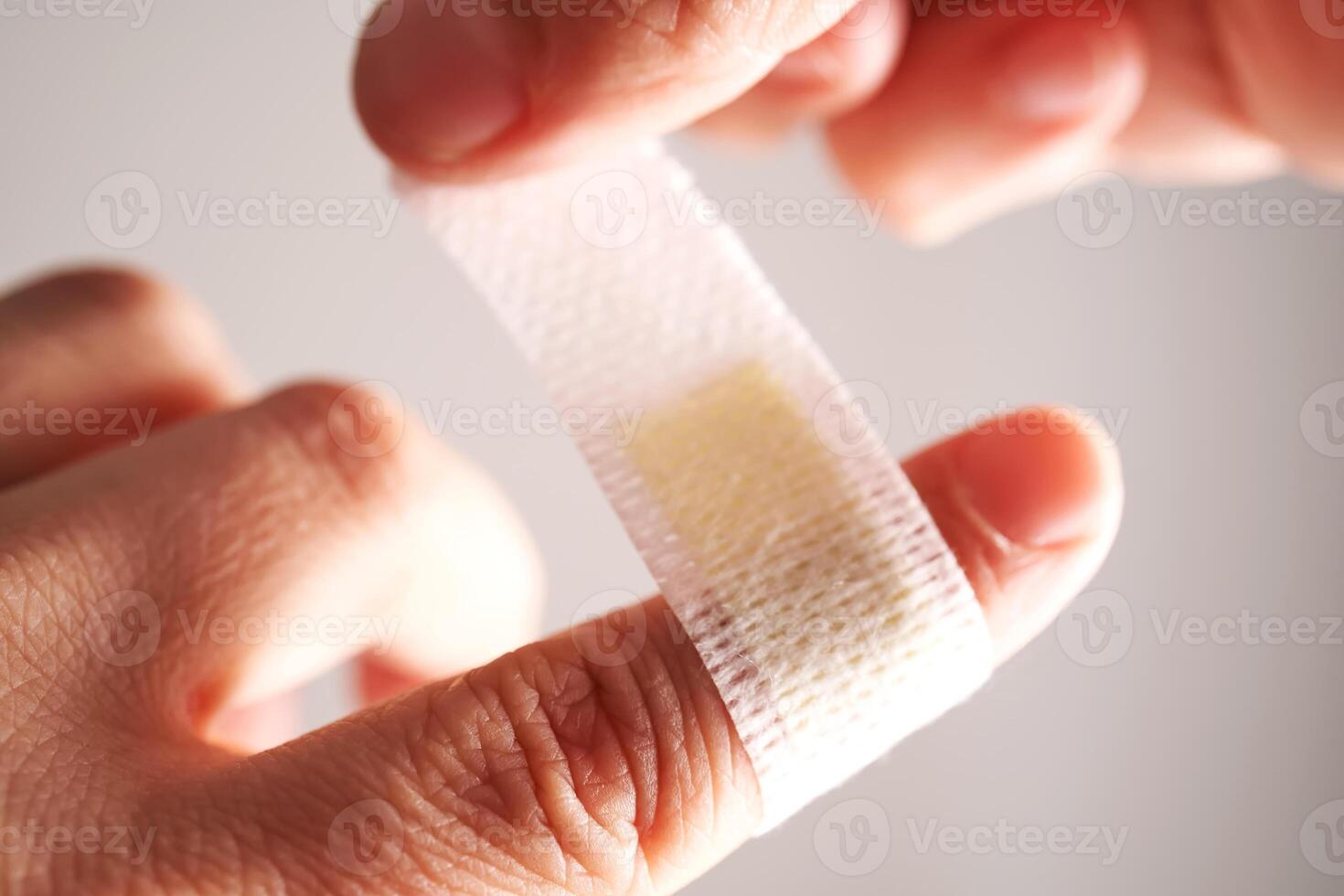 Applying an adhesive plaster to a finger. Close-up. photo