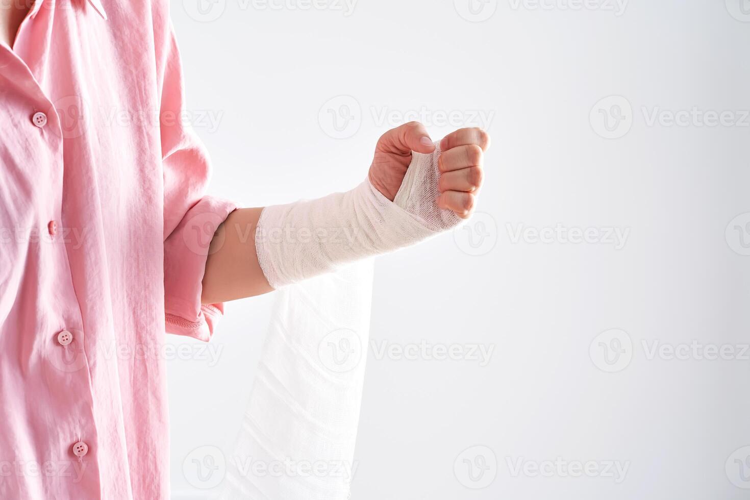 A woman in a pink shirt holds a bandage and puts a bandage on her arm. photo