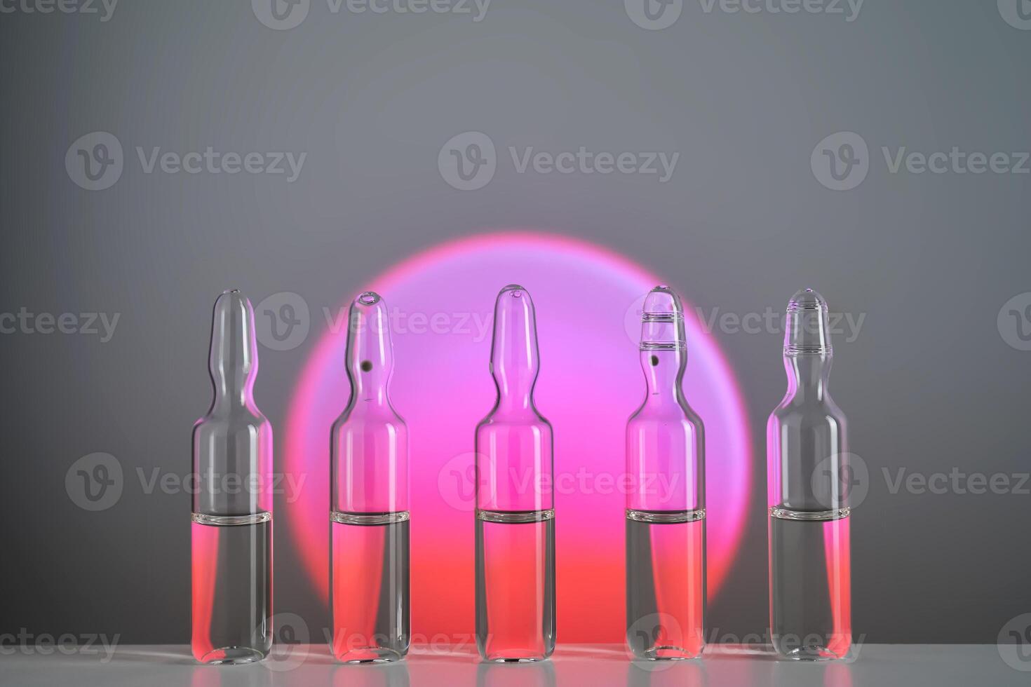 Several ampoules for injection with medicines on a pink background. photo