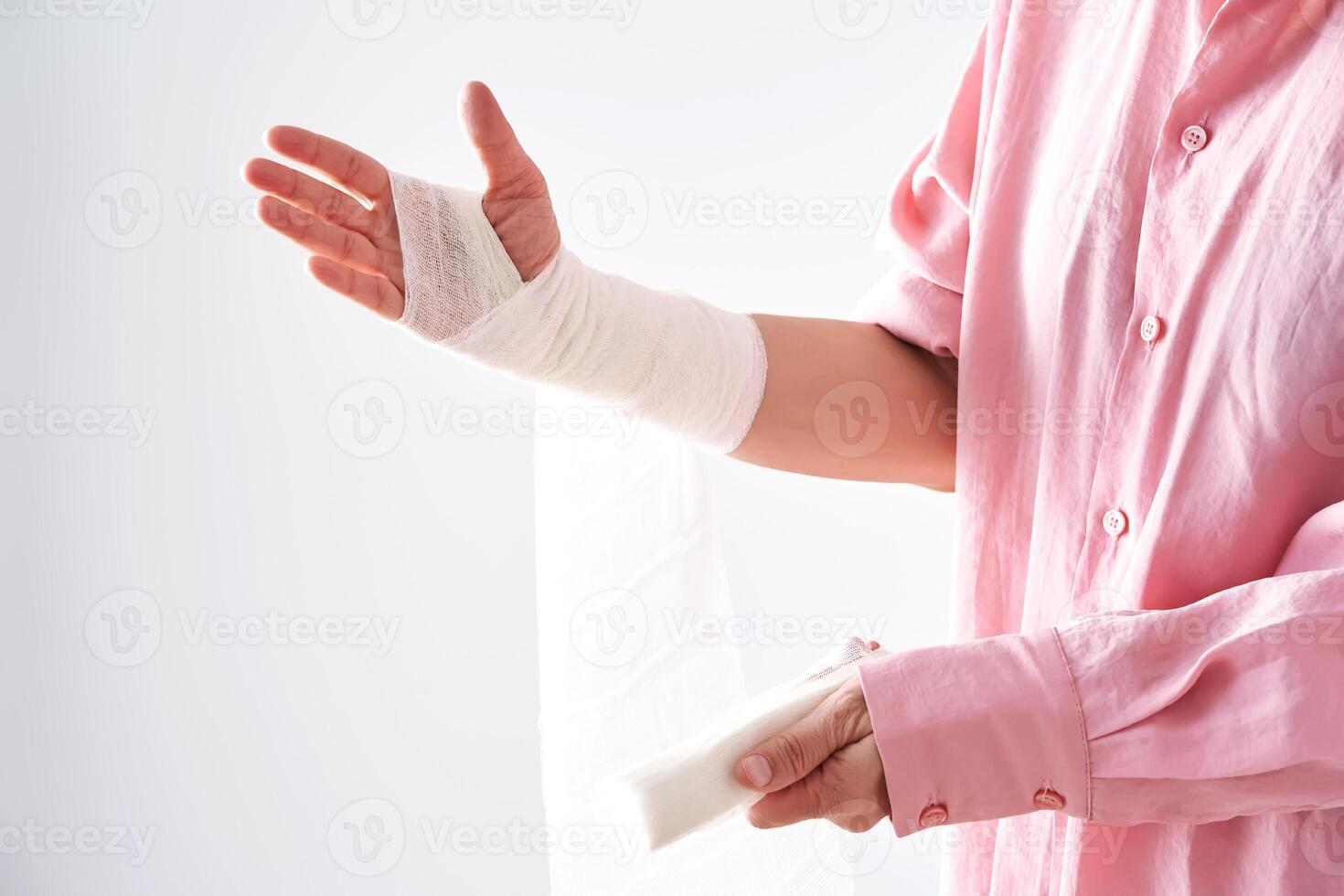 A woman in a pink shirt holds a bandage and puts a bandage on her arm. photo