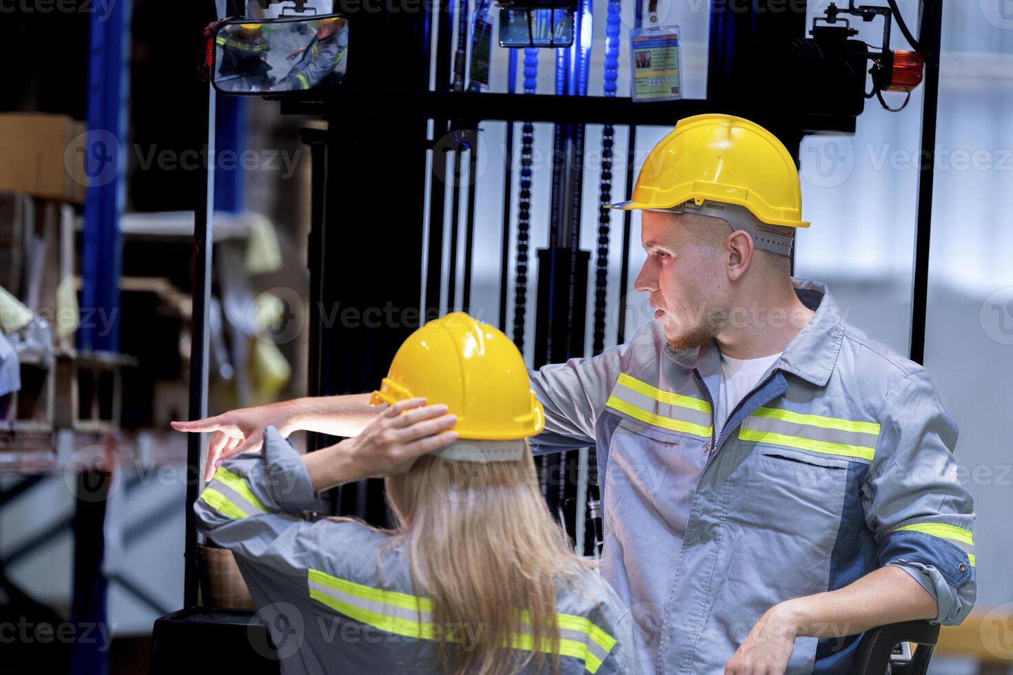 Two male and female factory checkers are discussing work on a warehouse truck. While working in a warehouse for industrial products photo