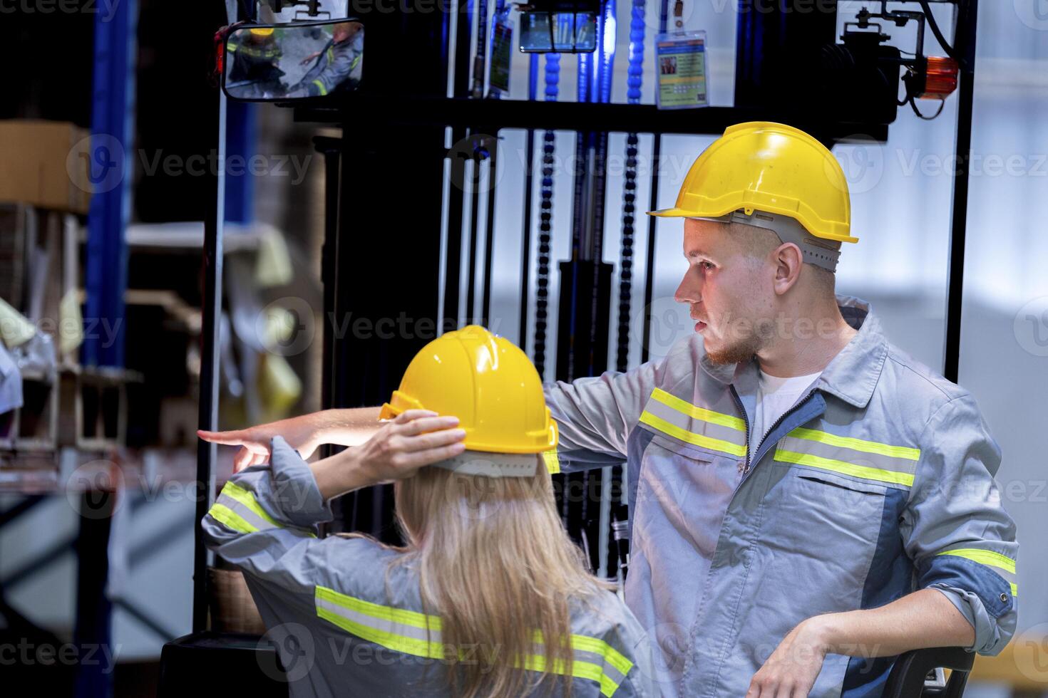 Two male and female factory checkers are discussing work on a warehouse truck. While working in a warehouse for industrial products photo
