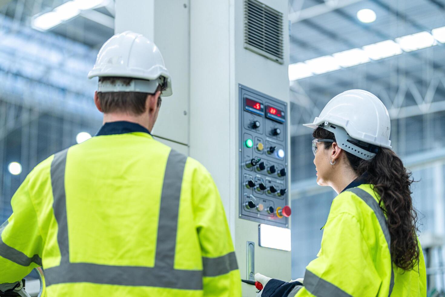 Male and female engineers in neat work clothes prepare and control the production system of large modern machines in a factory producing industrial technology products. photo