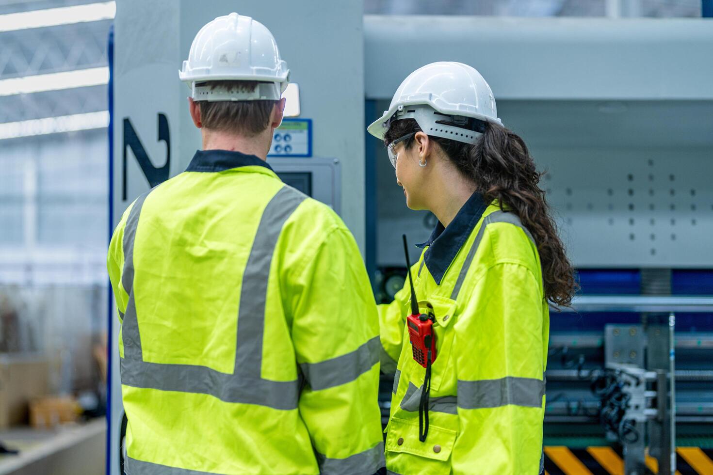 Male and female engineers in neat work clothes prepare and control the production system of large modern machines in a factory producing industrial technology products. photo