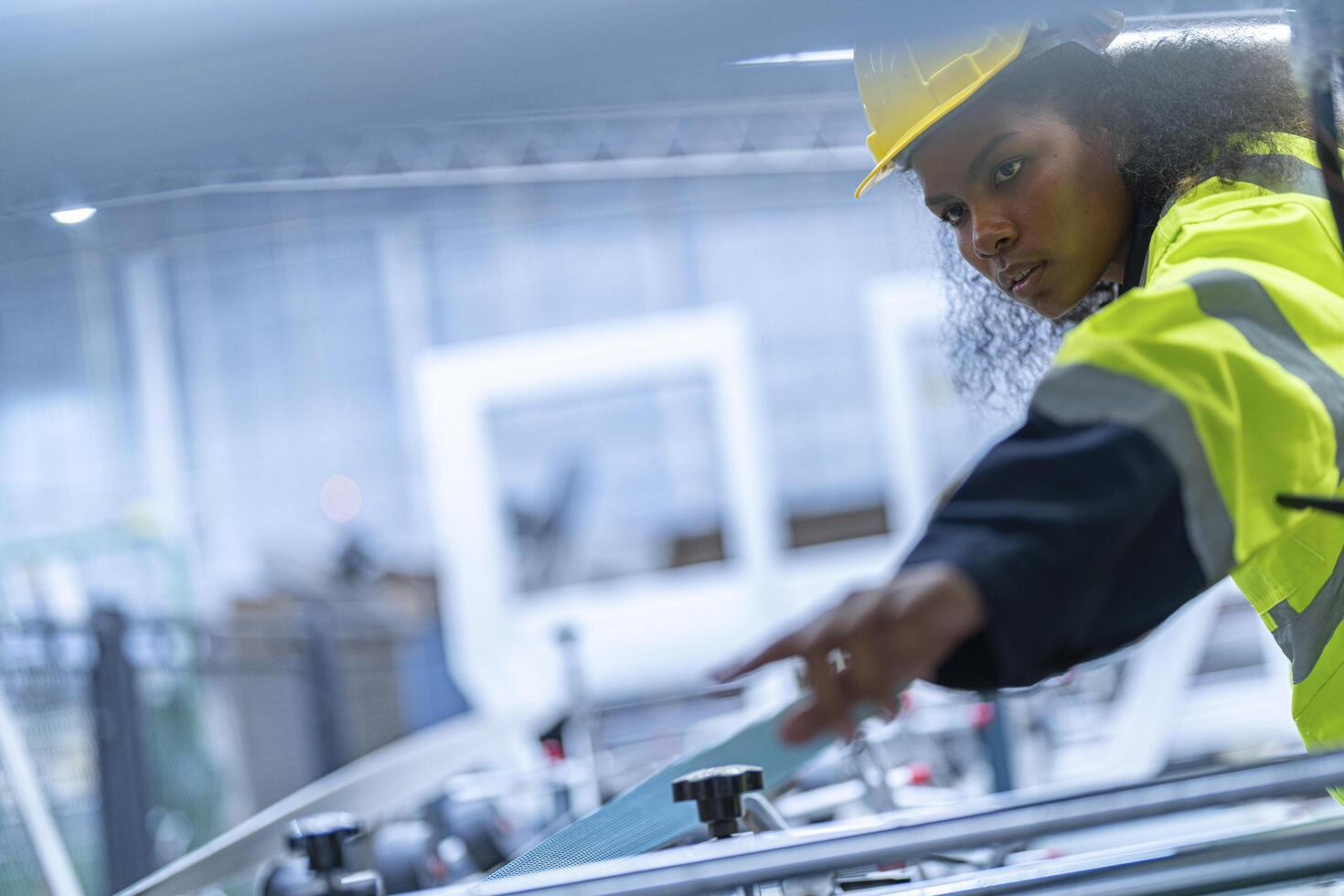 Portrait of African woman worker beautiful face with eye confident and wearing working suite dress and safety helmet at heavy machine in industry factory. Engineer worker concentrate on workplace. photo