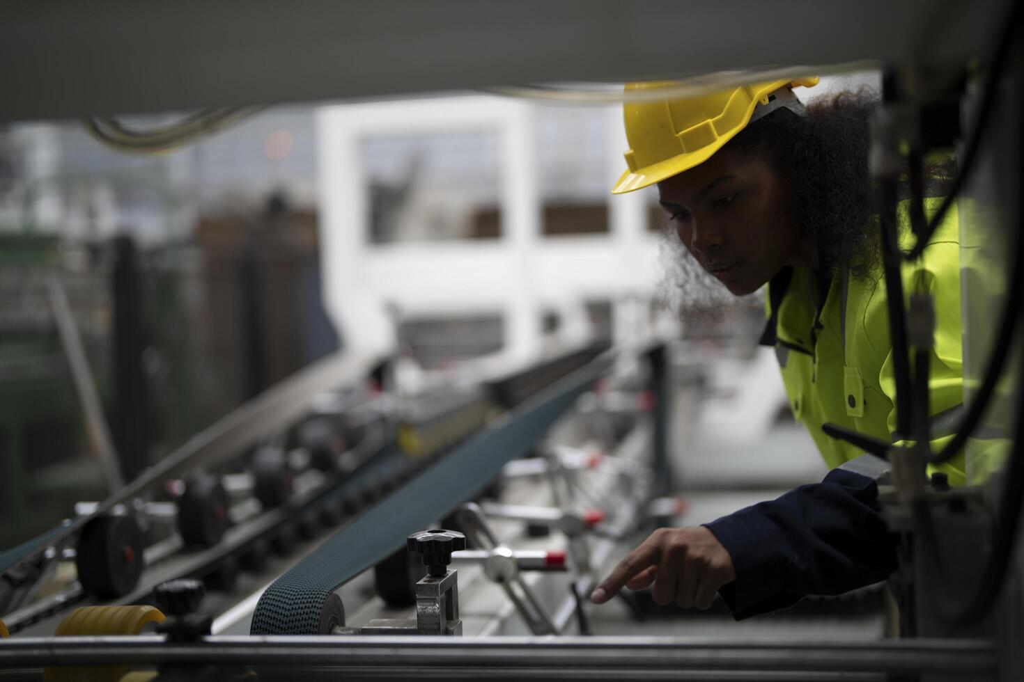 Portrait of African woman worker beautiful face with eye confident and wearing working suite dress and safety helmet at heavy machine in industry factory. Engineer worker concentrate on workplace. photo