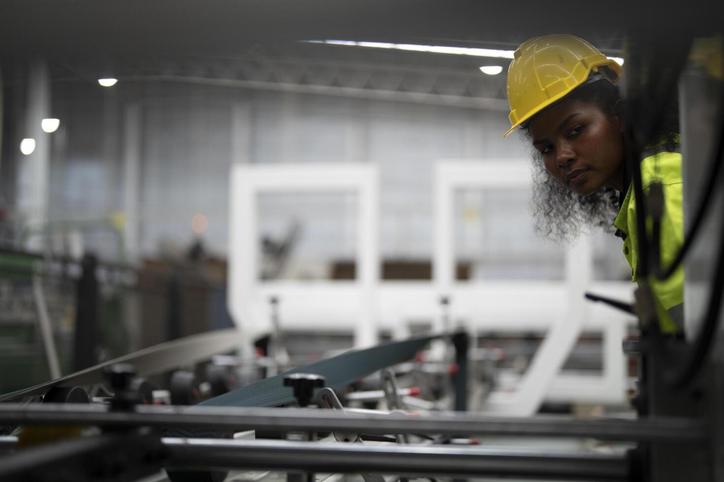 Portrait of African woman worker beautiful face with eye confident and wearing working suite dress and safety helmet at heavy machine in industry factory. Engineer worker concentrate on workplace. photo