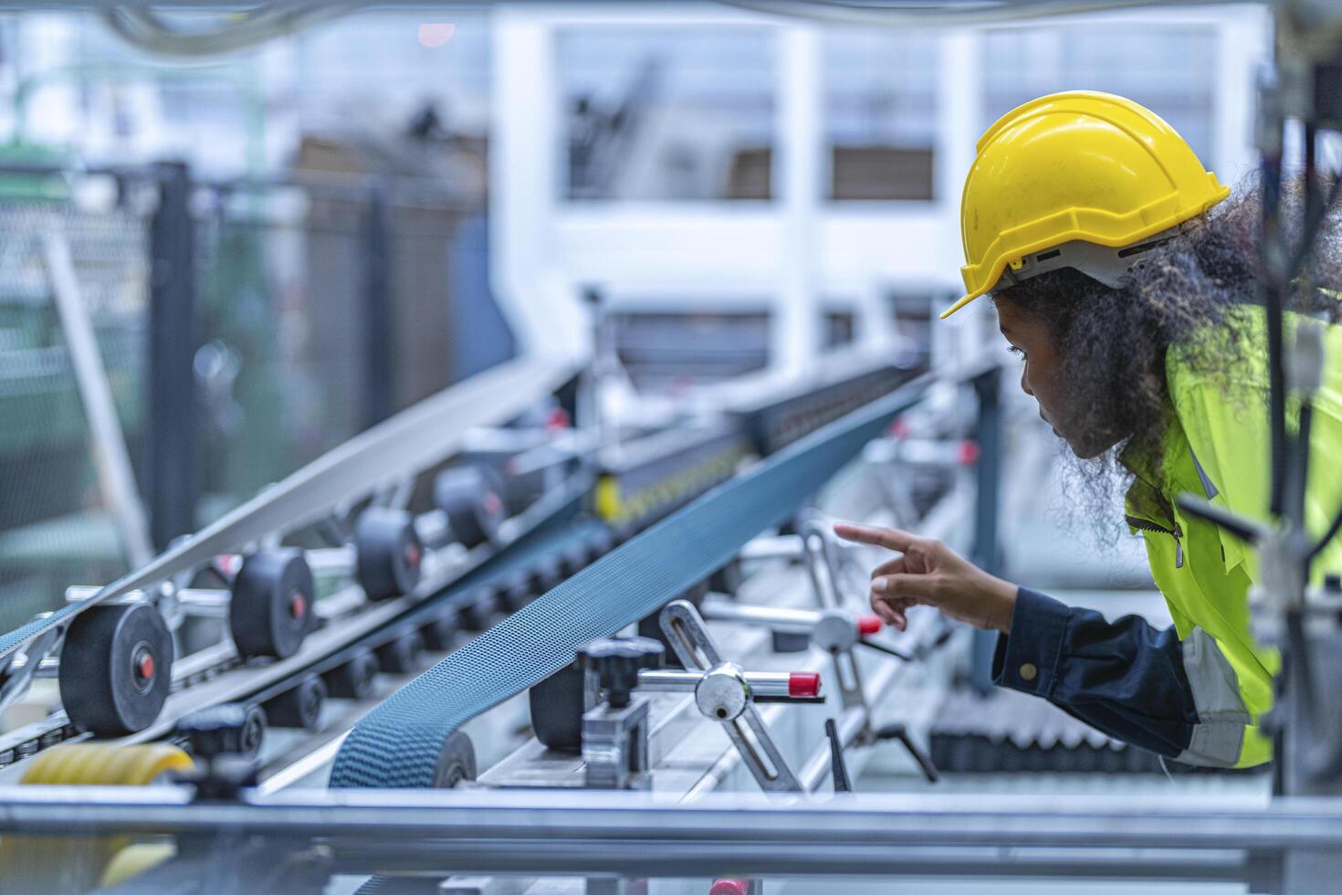 Portrait of African woman worker beautiful face with eye confident and wearing working suite dress and safety helmet at heavy machine in industry factory. Engineer worker concentrate on workplace. photo