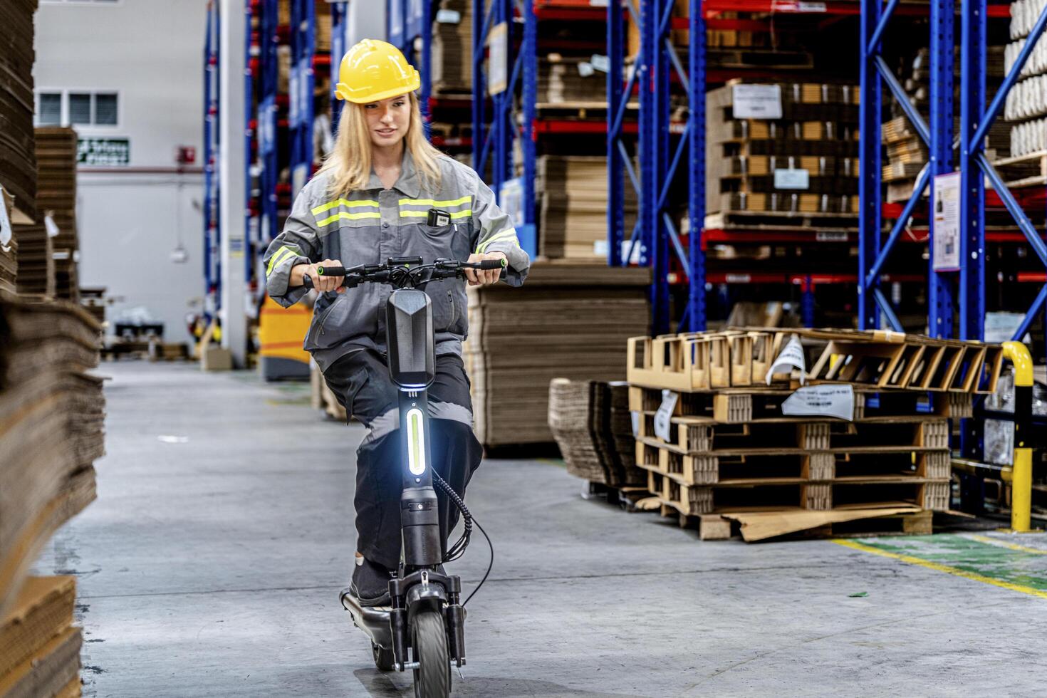 woman riding electric bicycle and checking stock items for shipping. female inspecting the store factory. Logistics employees holding folders at on site warehouse area for shipping transportation. photo