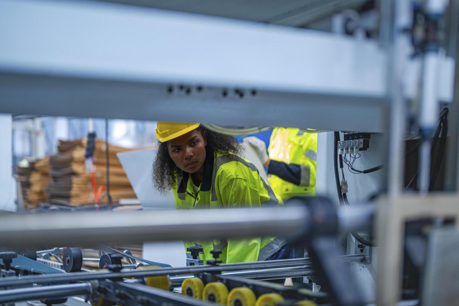 Portrait of African woman worker beautiful face with eye confident and wearing working suite dress and safety helmet at heavy machine in industry factory. Engineer worker concentrate on workplace. photo