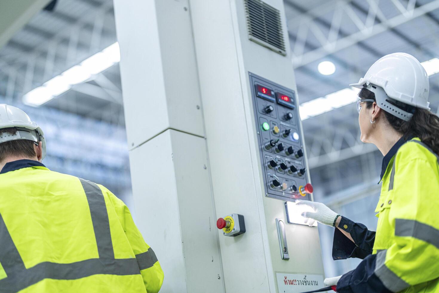 Male and female engineers in neat work clothes prepare and control the production system of large modern machines in a factory producing industrial technology products. photo