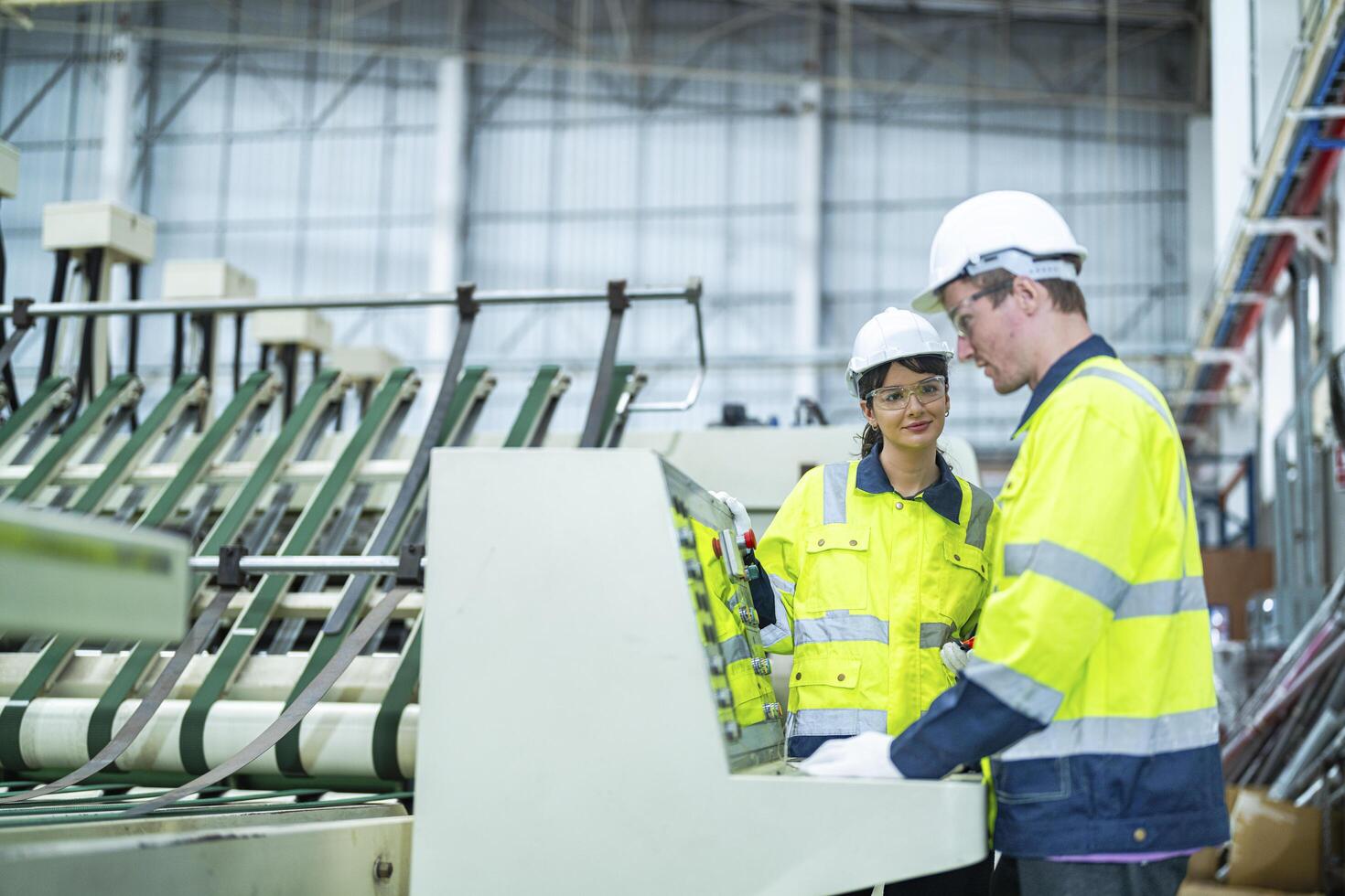 Male and female engineers in neat work clothes prepare and control the production system of large modern machines in a factory producing industrial technology products. photo