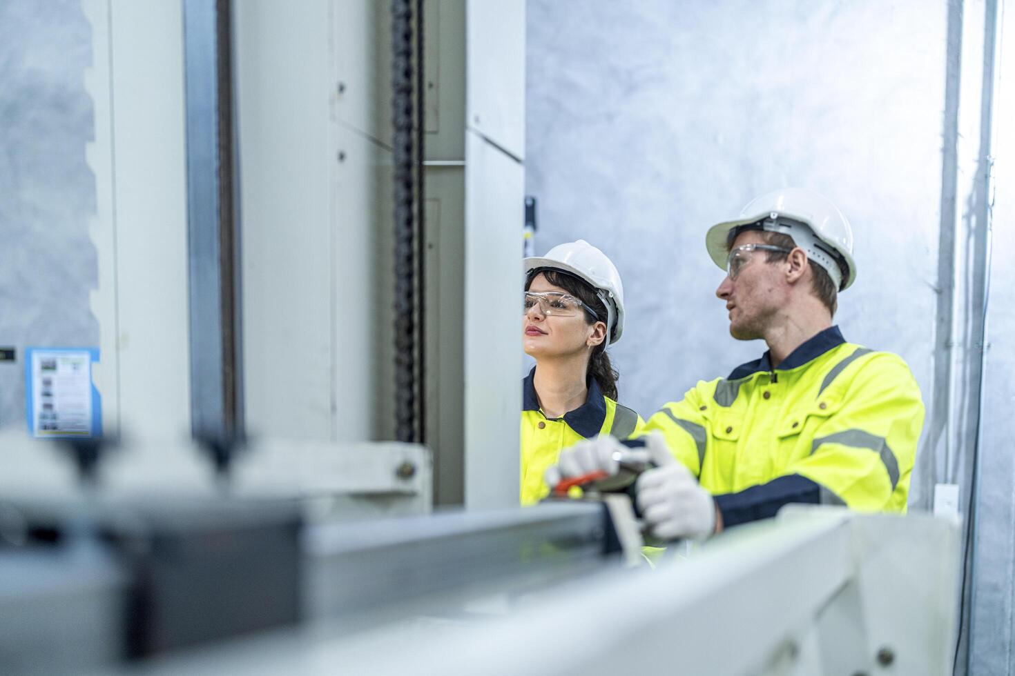Male and female engineers in neat work clothes prepare and control the production system of large modern machines in a factory producing industrial technology products. photo