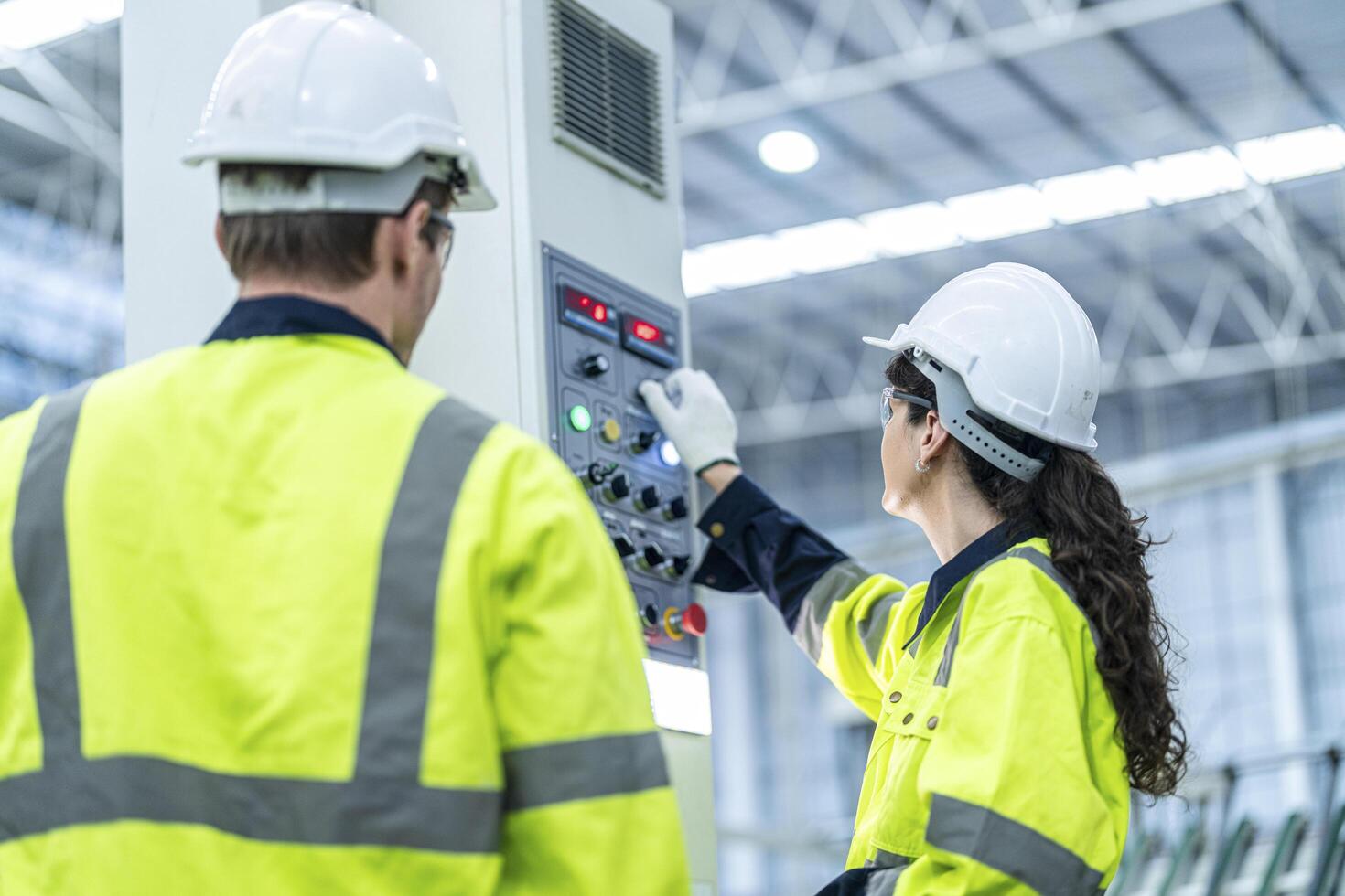 Male and female engineers in neat work clothes prepare and control the production system of large modern machines in a factory producing industrial technology products. photo