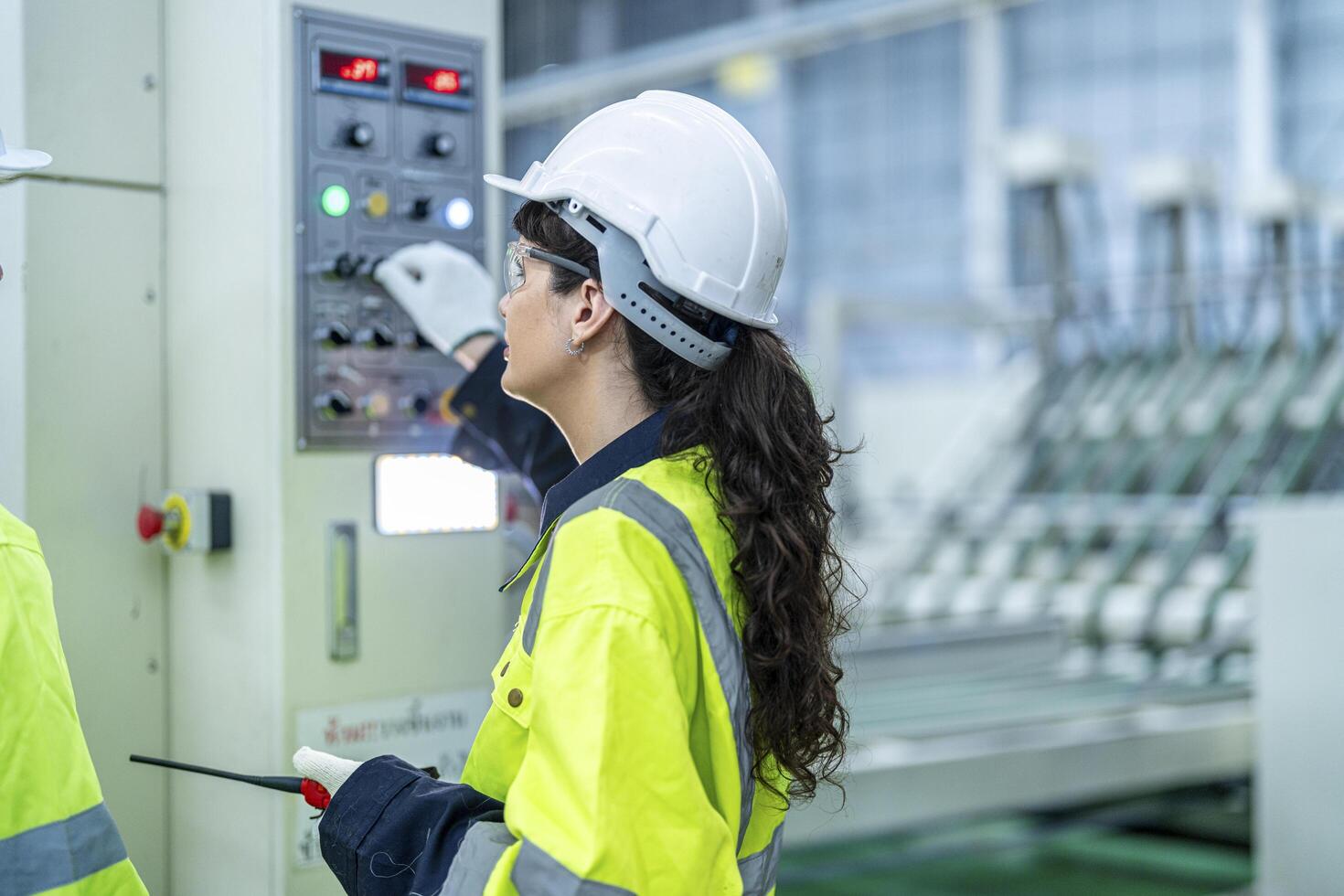 Male and female engineers in neat work clothes prepare and control the production system of large modern machines in a factory producing industrial technology products. photo