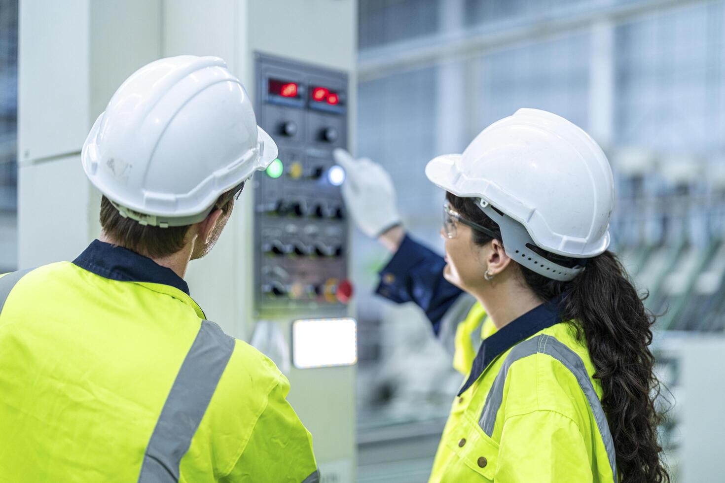Male and female engineers in neat work clothes prepare and control the production system of large modern machines in a factory producing industrial technology products. photo