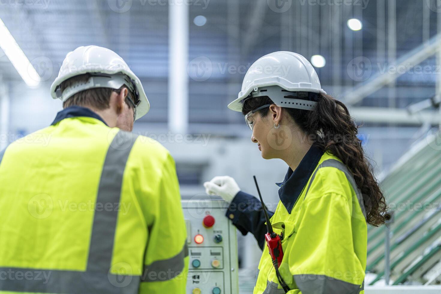 Male and female engineers in neat work clothes prepare and control the production system of large modern machines in a factory producing industrial technology products. photo