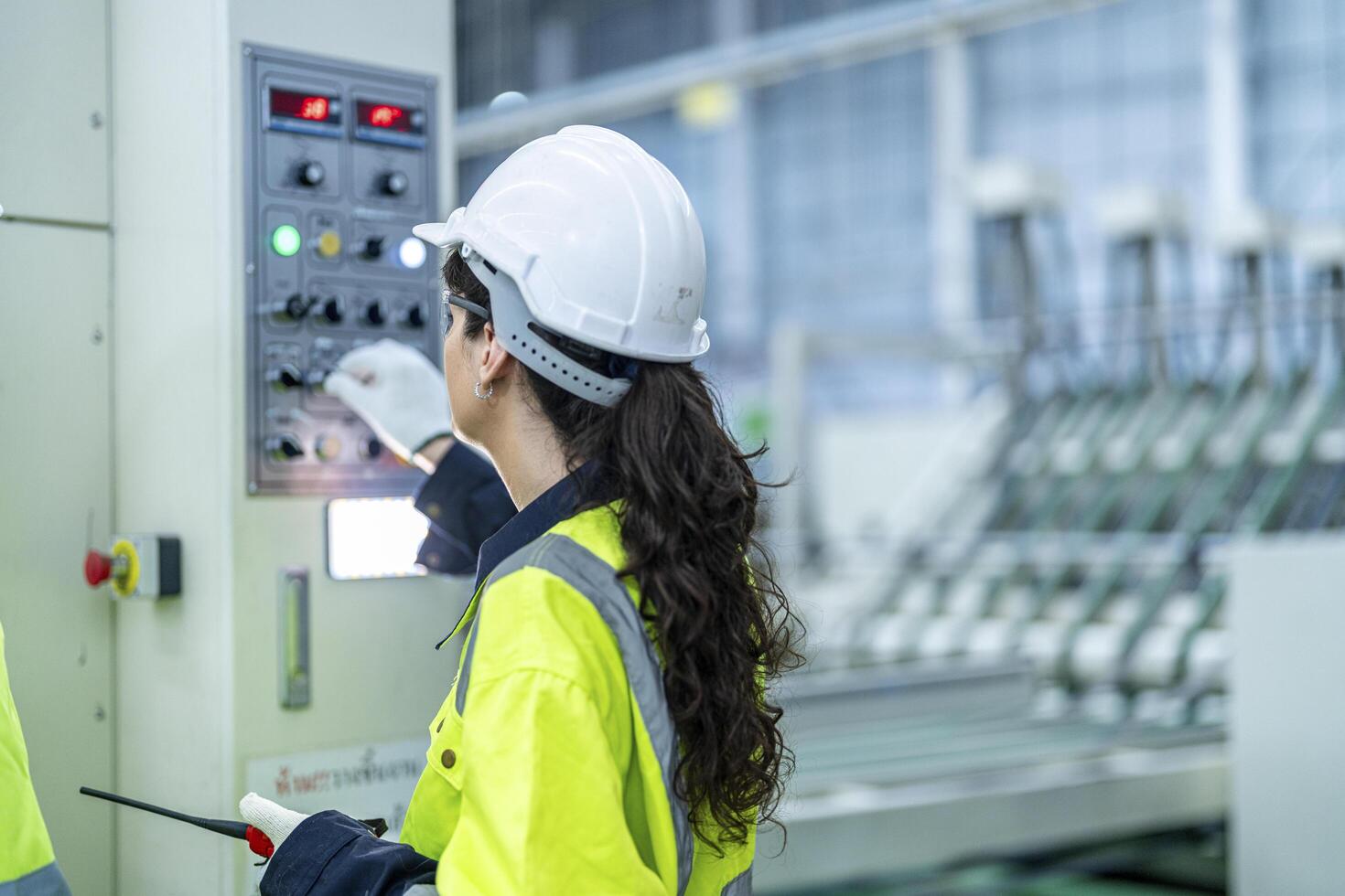 Male and female engineers in neat work clothes prepare and control the production system of large modern machines in a factory producing industrial technology products. photo