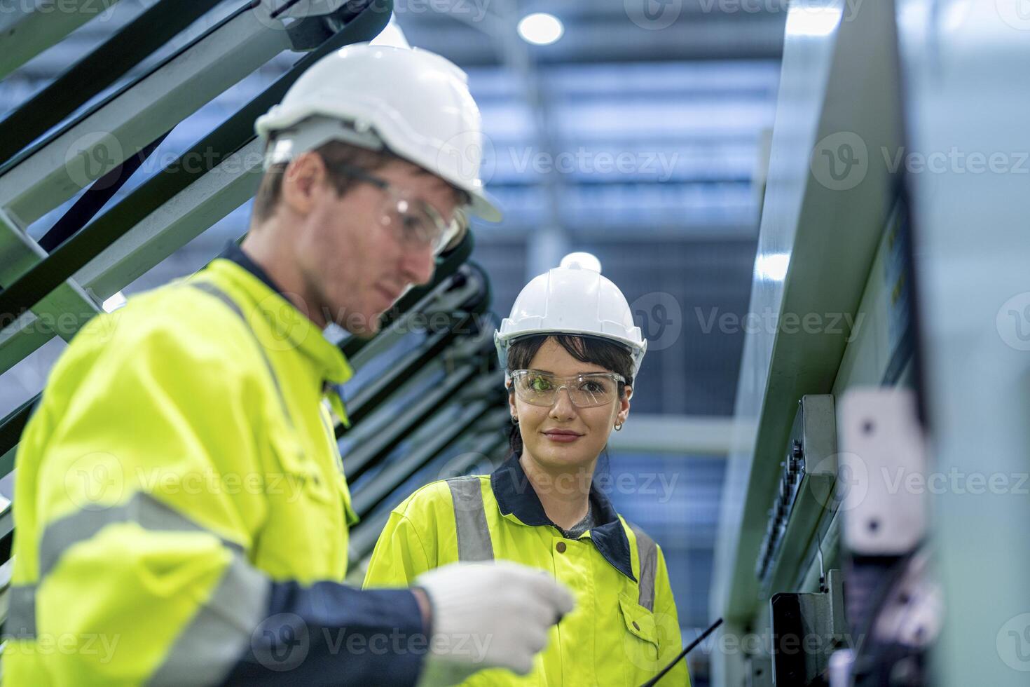 Male and female engineers in neat work clothes prepare and control the production system of large modern machines in a factory producing industrial technology products. photo