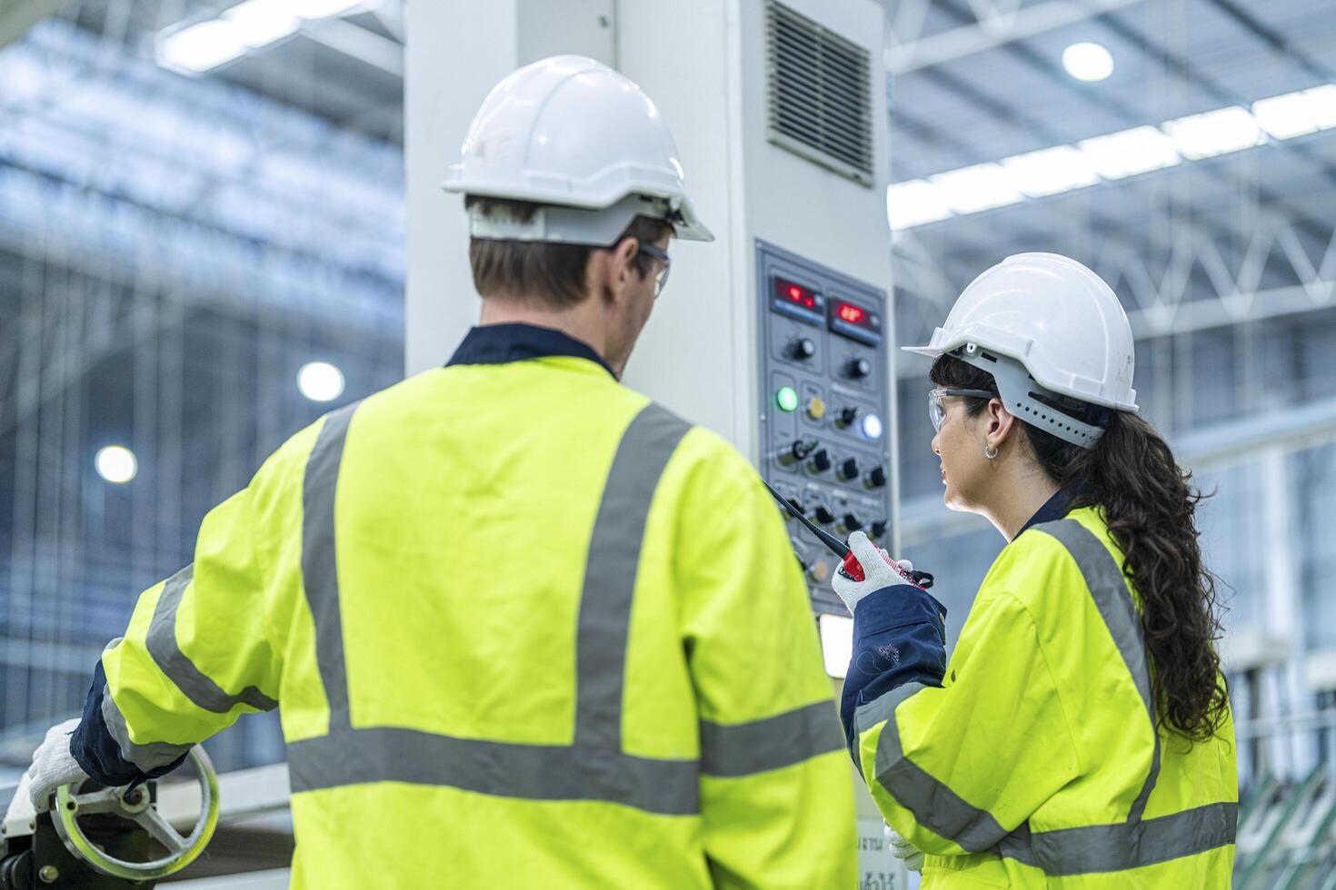 Male and female engineers in neat work clothes prepare and control the production system of large modern machines in a factory producing industrial technology products. photo